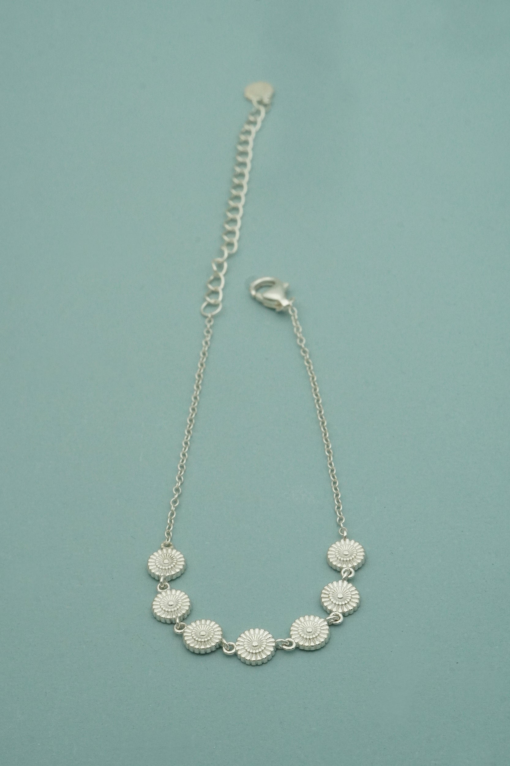 sterling silver bracelet with flower pendants on a blue background
