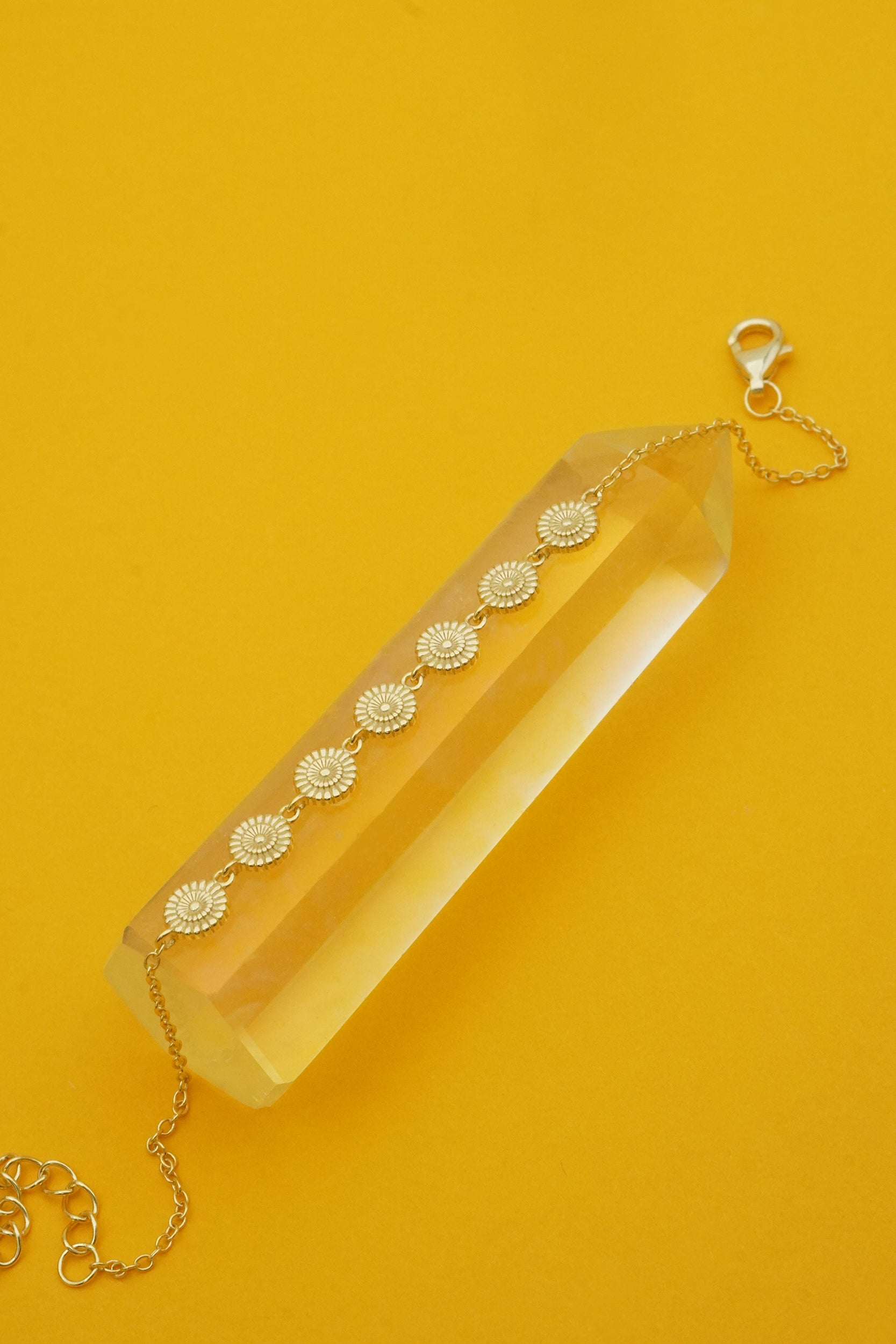 Clear crystal with gold floral bracelet chain on a yellow background