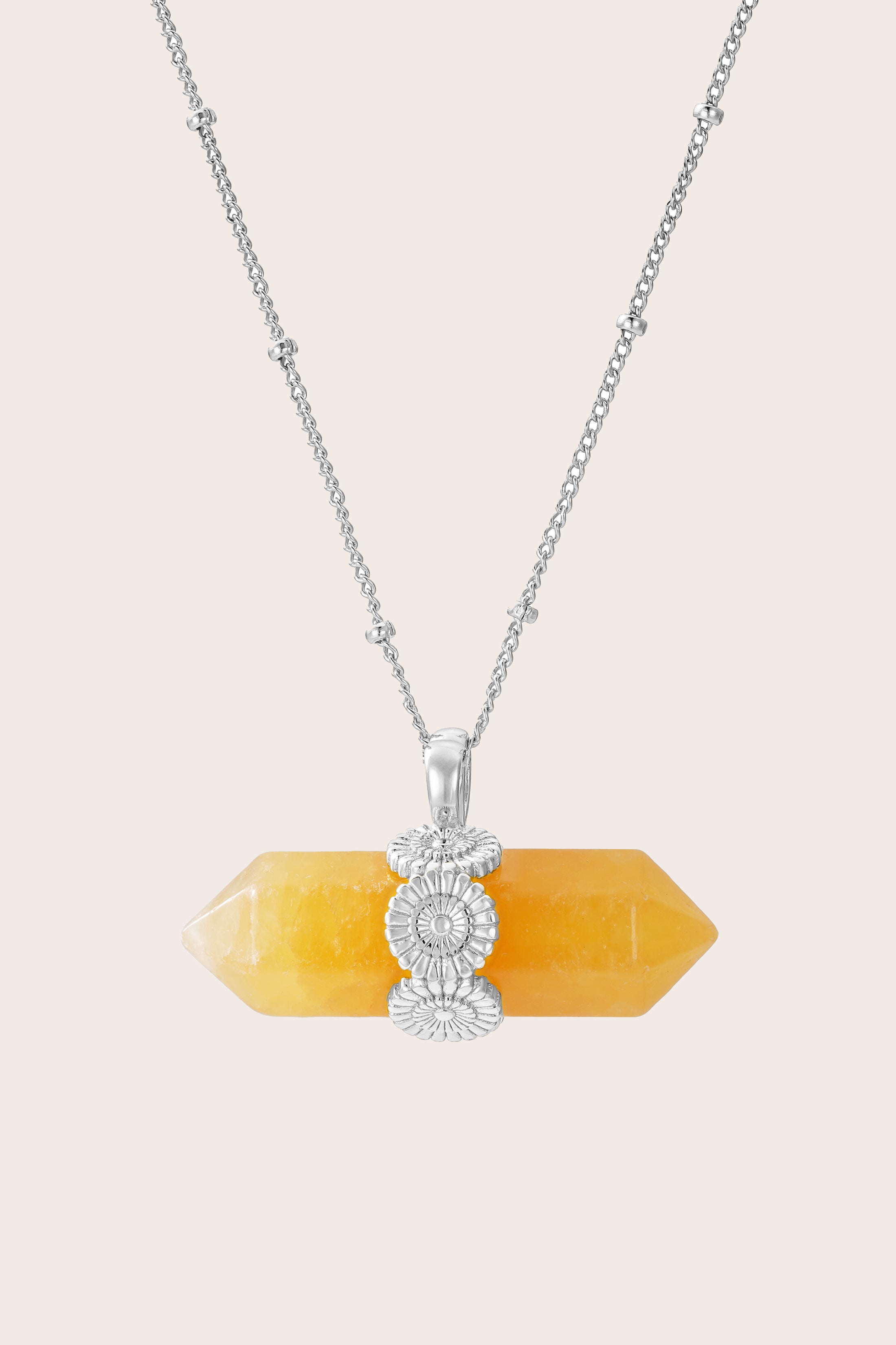 Necklace with a yellow crystal pendant and silver floral design on a beige background