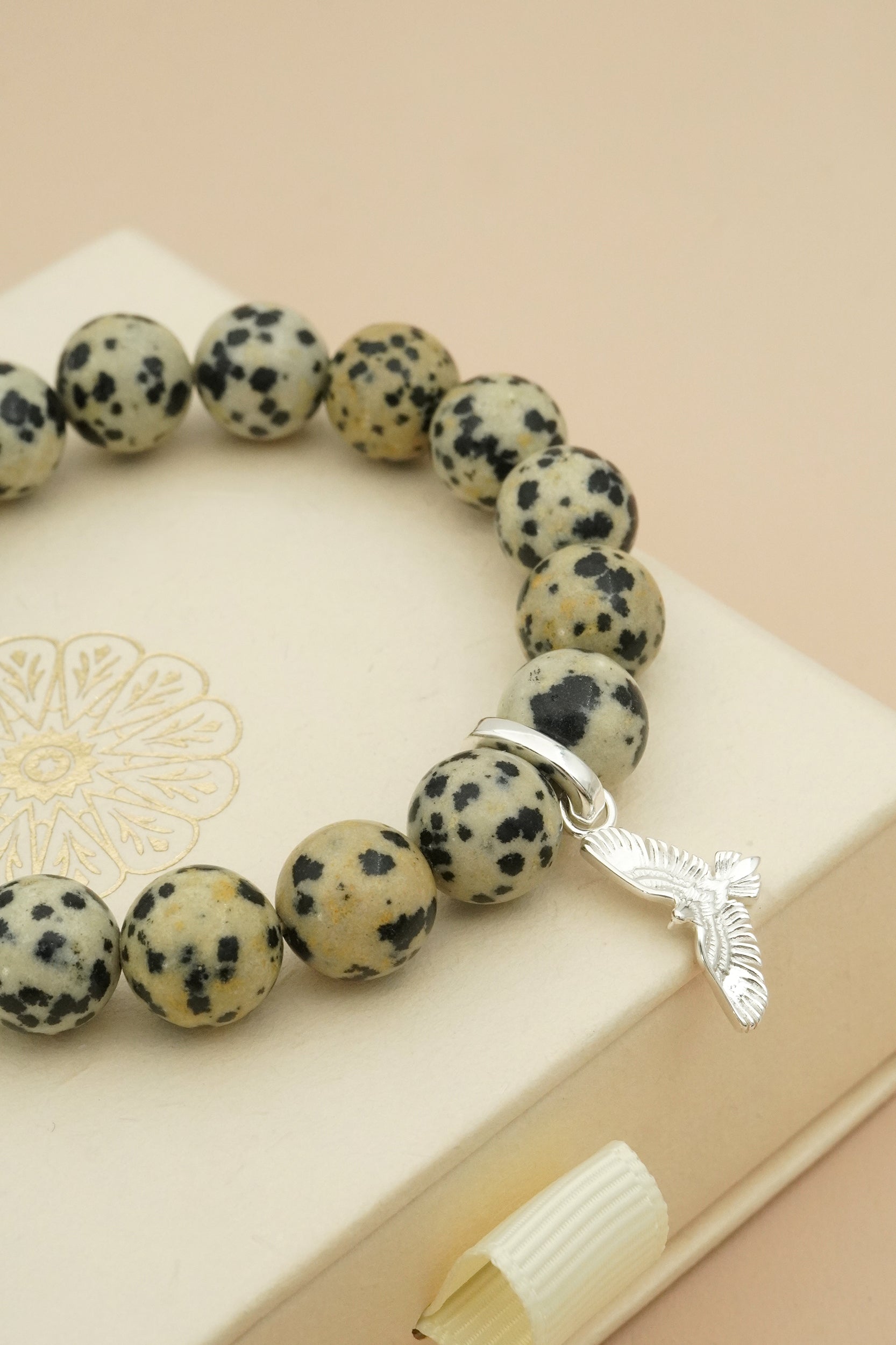 Beaded bracelet with a silver eagle charm on a beige surface