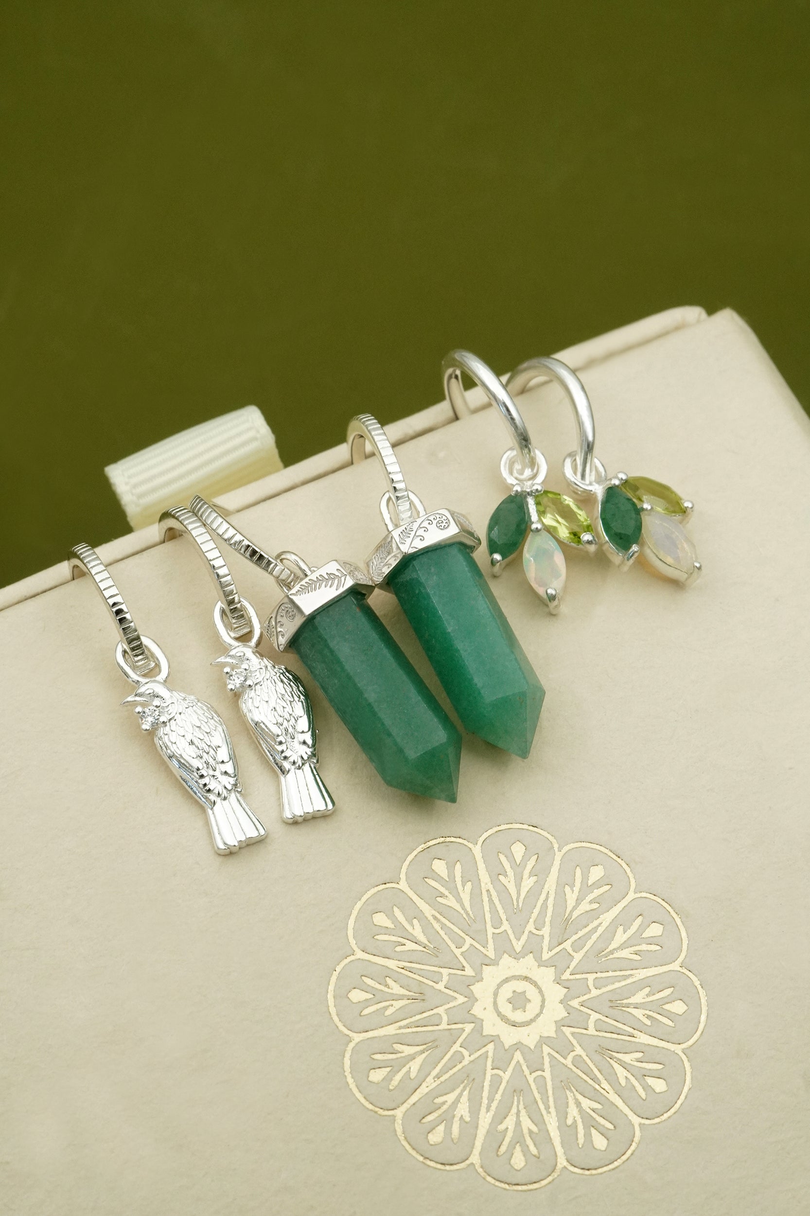 Green crystal an d sterling silver nature inspired NZ forest earrings on a beige background