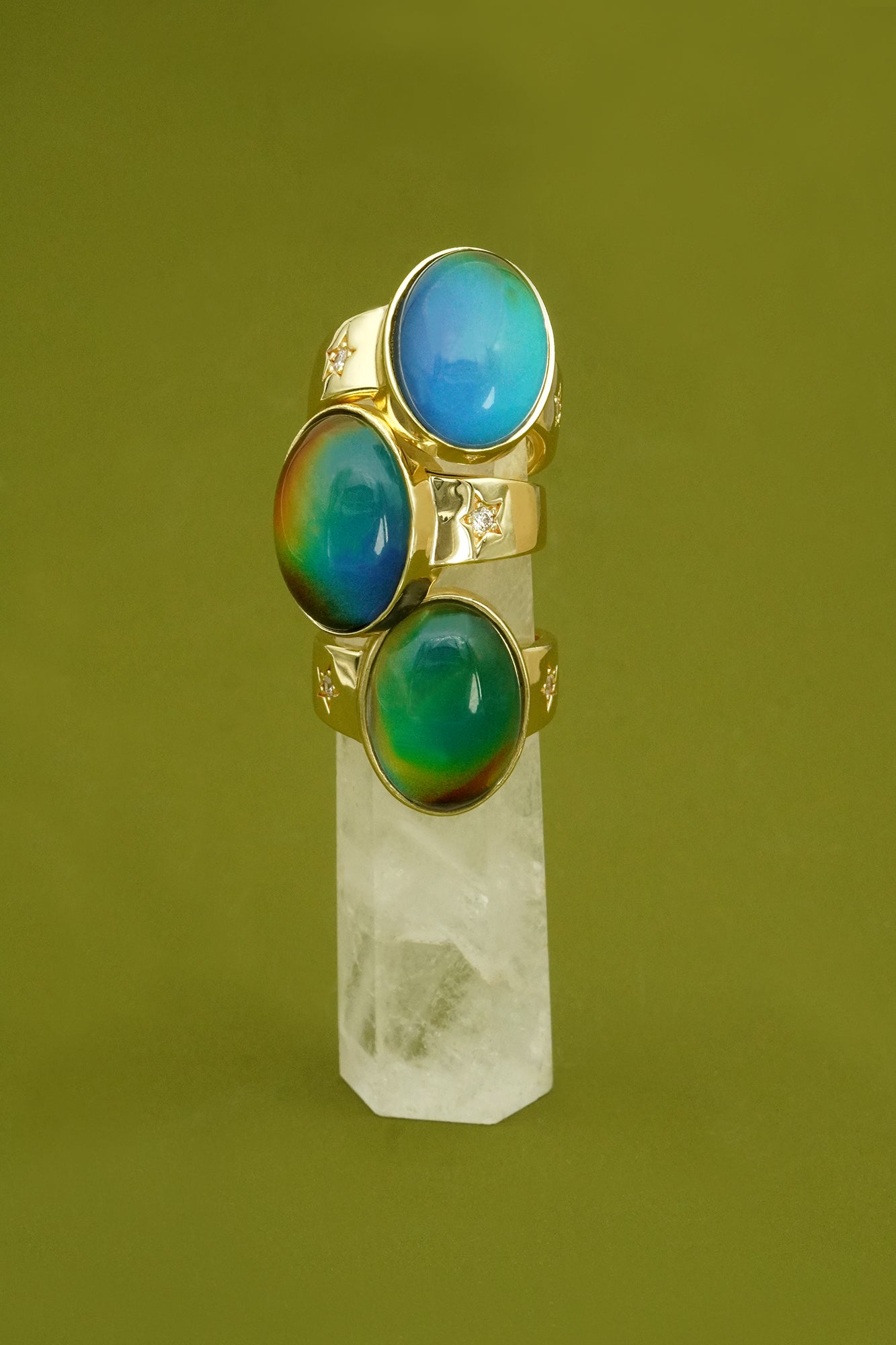 Gold ring with three colourful mood rings gemstones on a green background