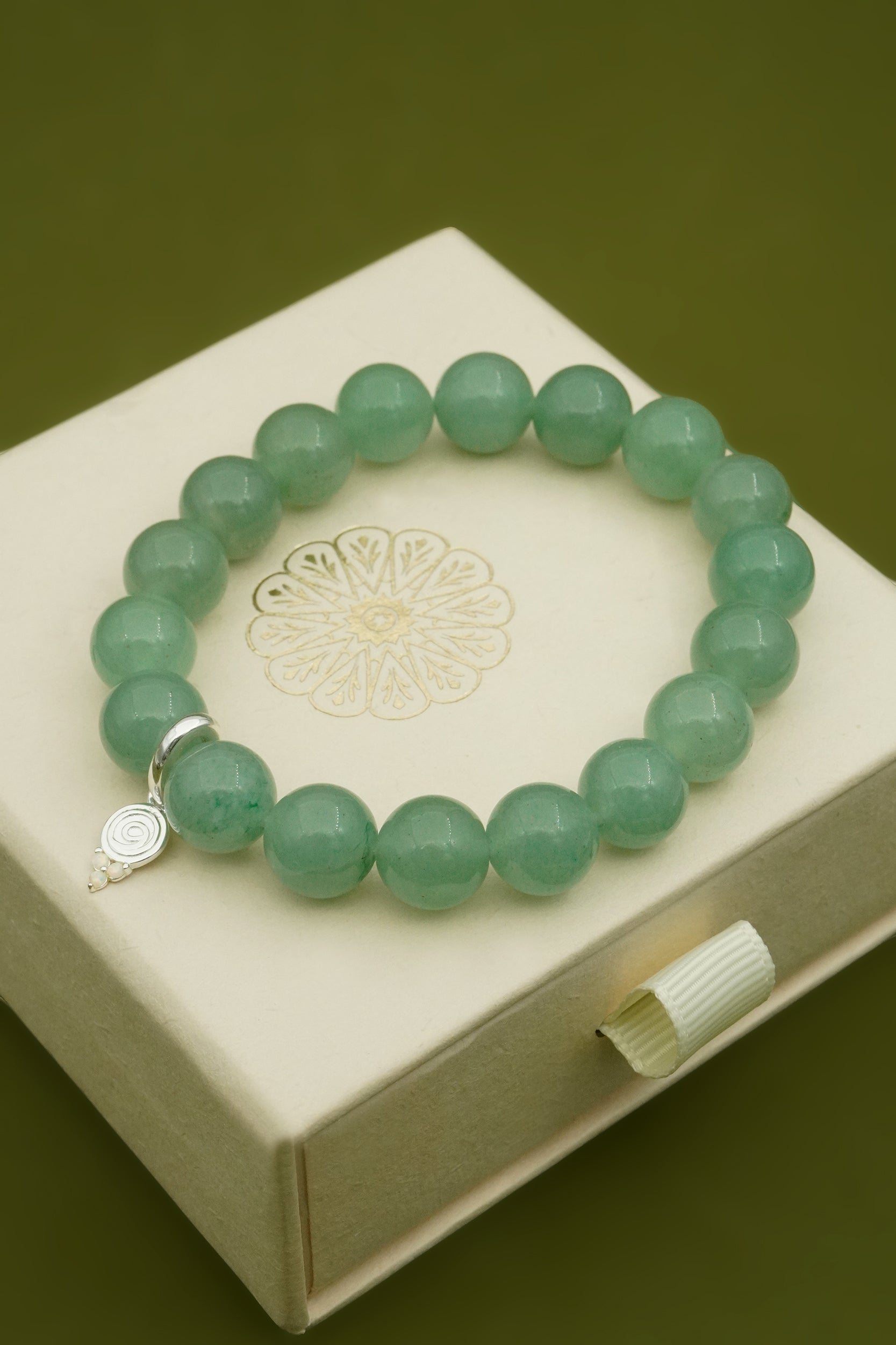 Green beaded bracelet on a white cloud nine jewellery box with a green background