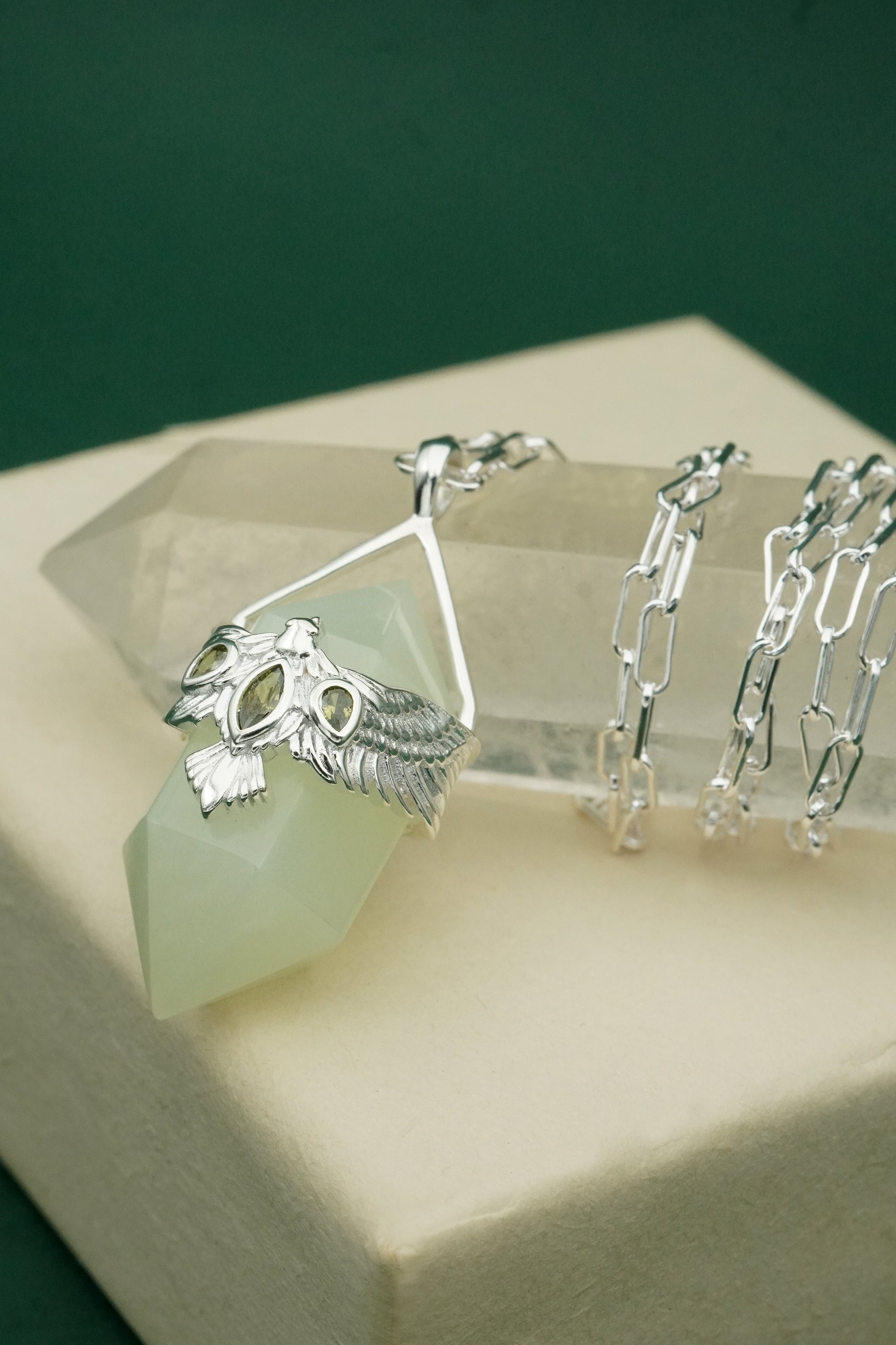 Silver bird jewellery set on a green crystal with a green background