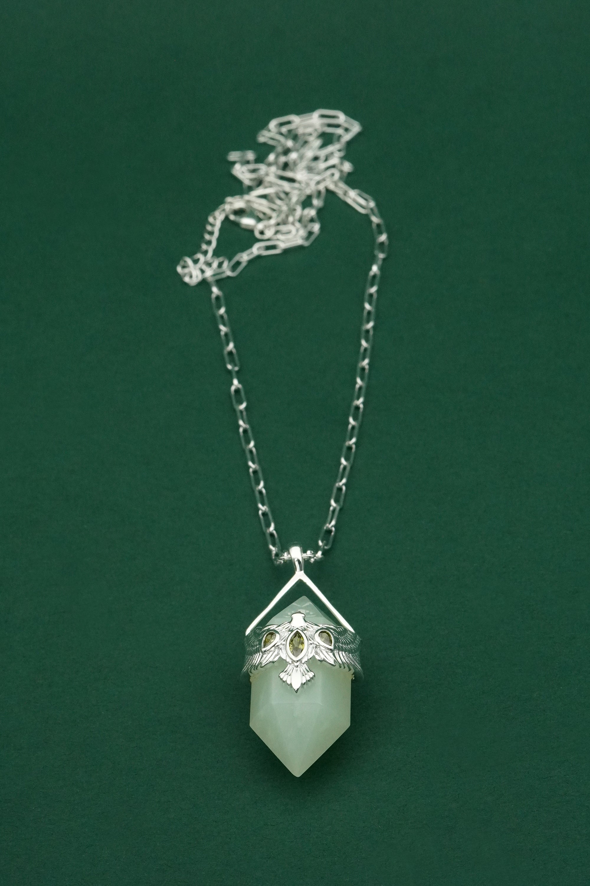 Necklace with a green crystal pendant on a green background