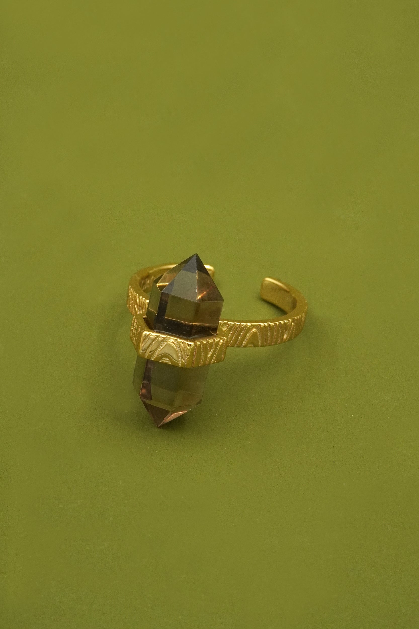 Gold ring with a central gemstone on a green background