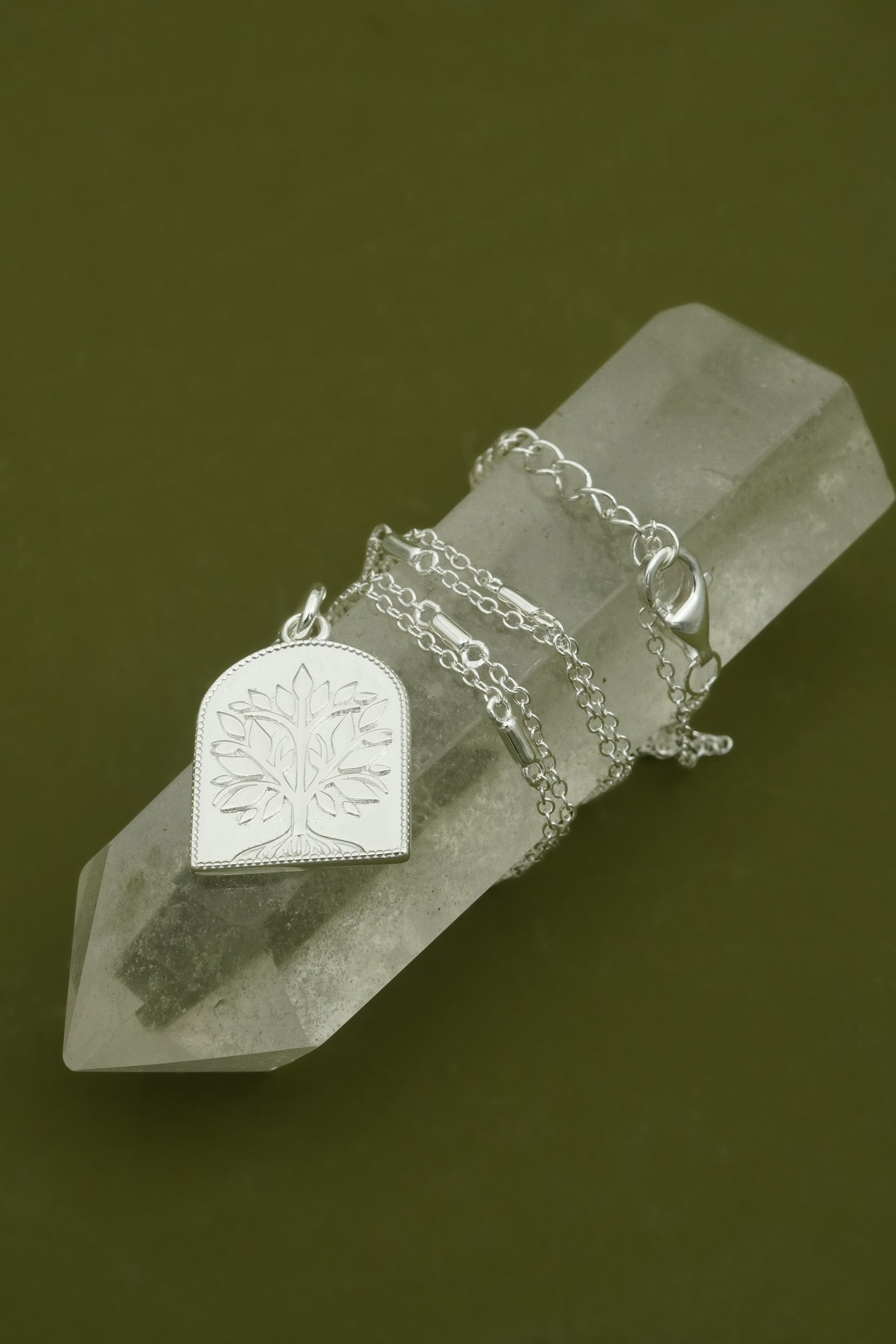 Sterling s
ilver tree of life necklace with a pendant on a crystal prism against a dark background