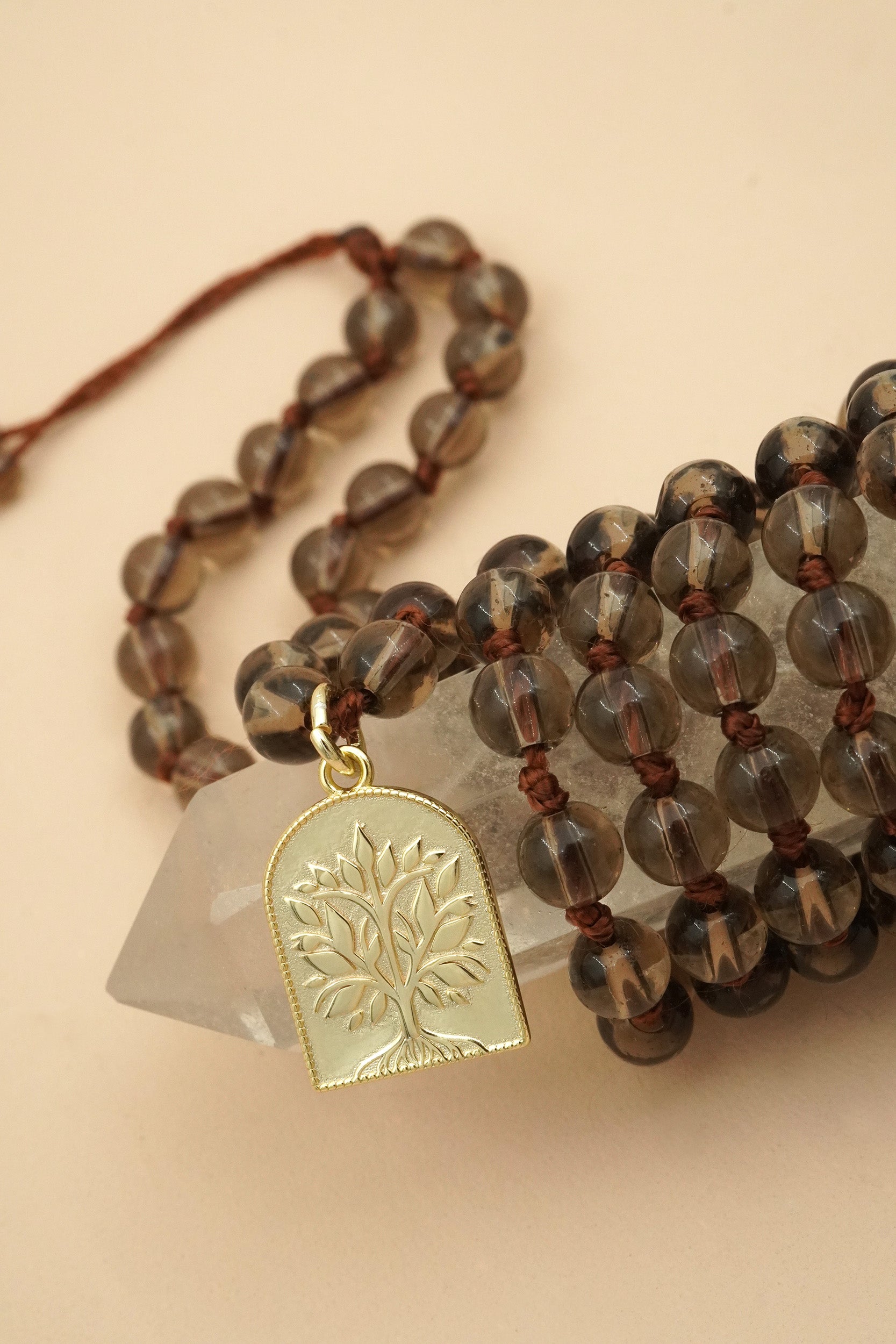 108 spiritual male prayer bead necklace with brown beads and a gold tree pendant on a beige background