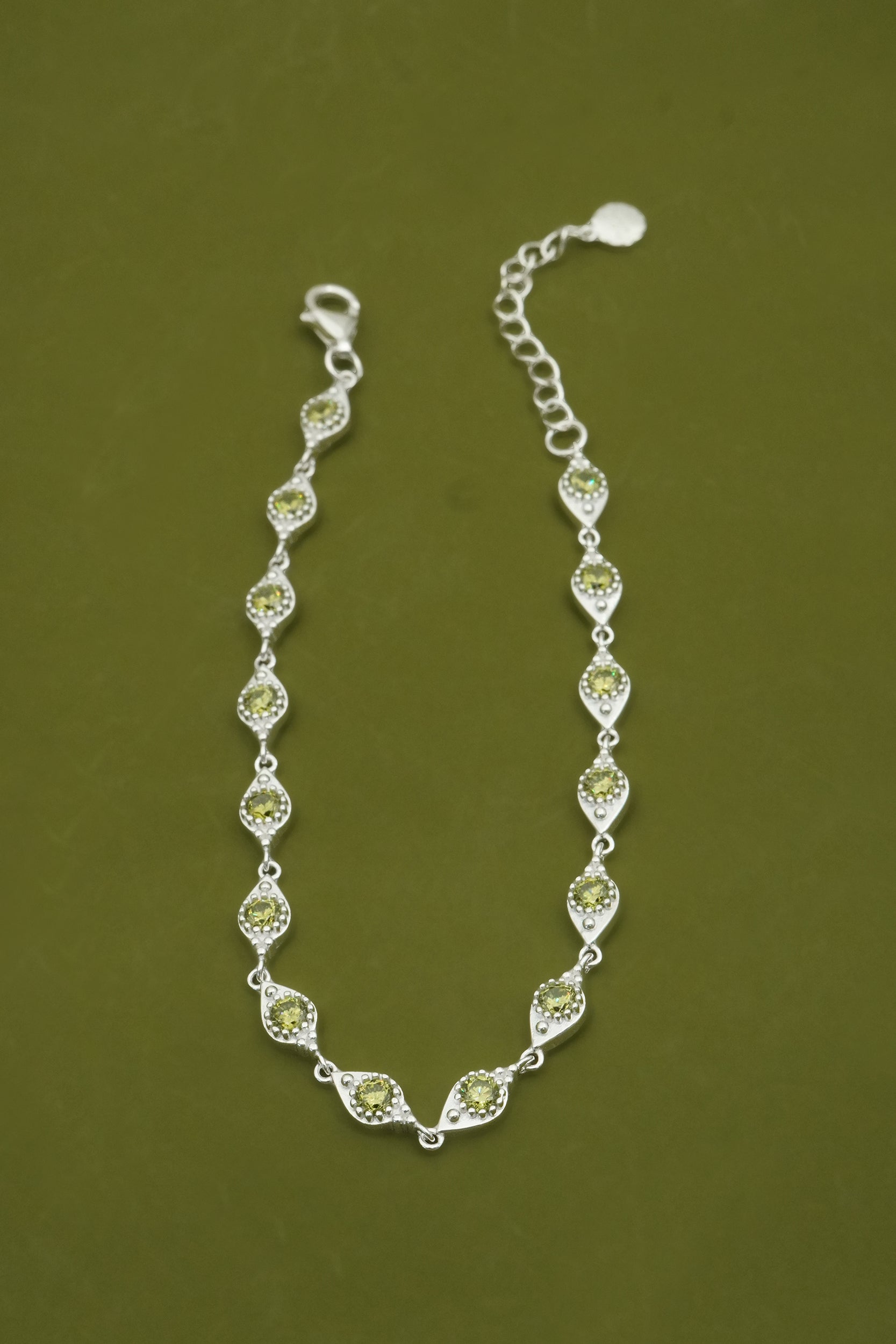 Silver bracelet with green gemstones on a green background