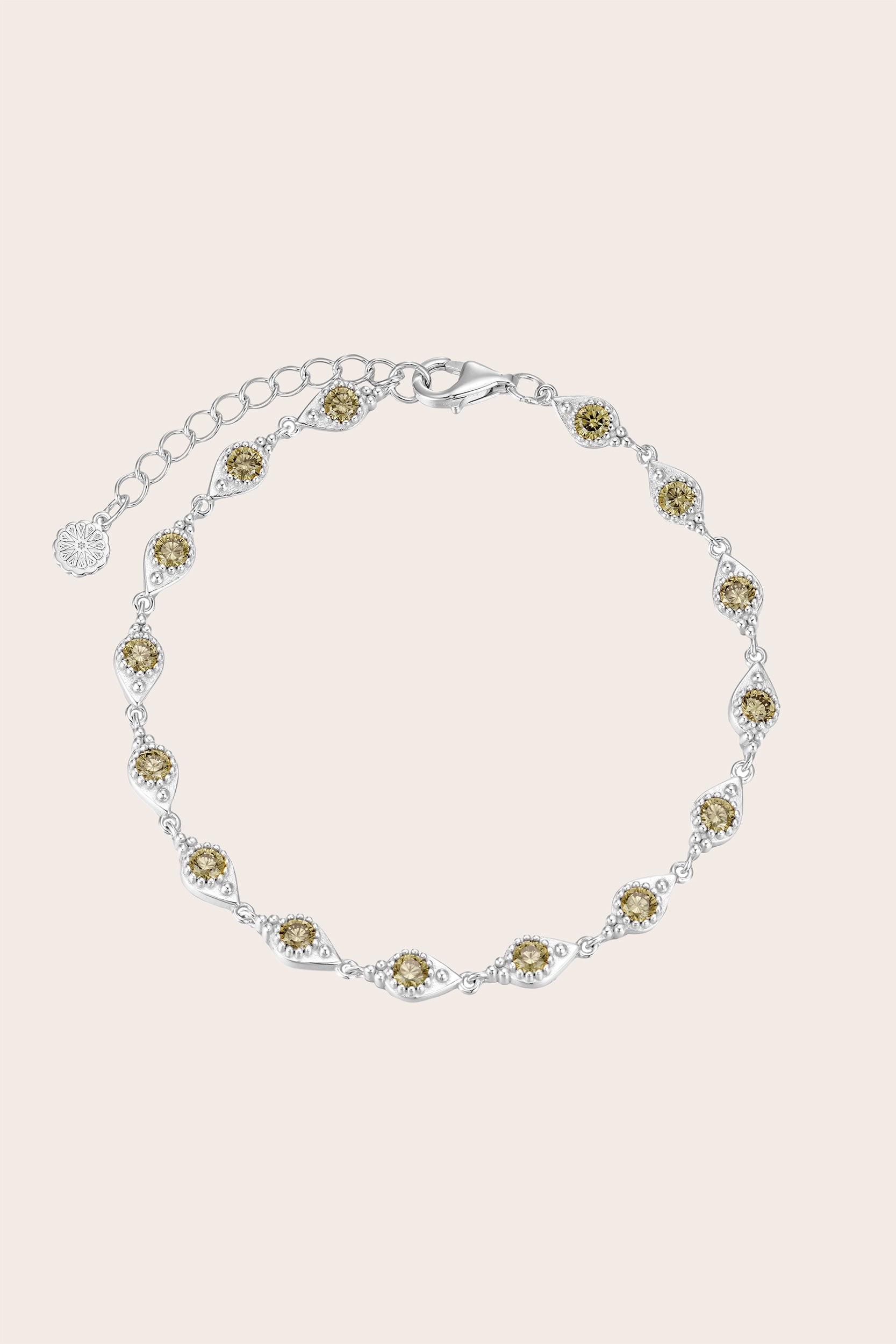 Silver bracelet with green gemstones on a light pink background