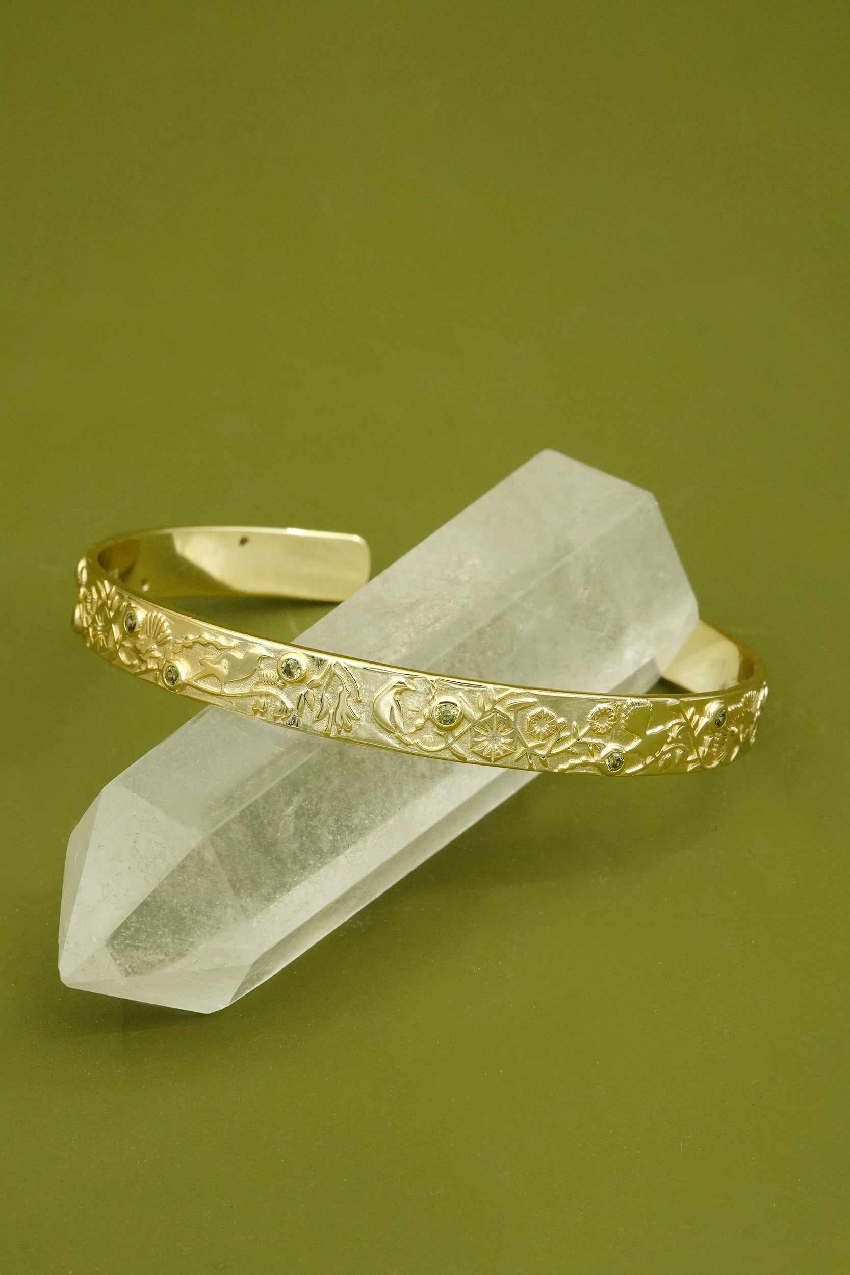Gold cuff bracelet on a crystal with a green background
