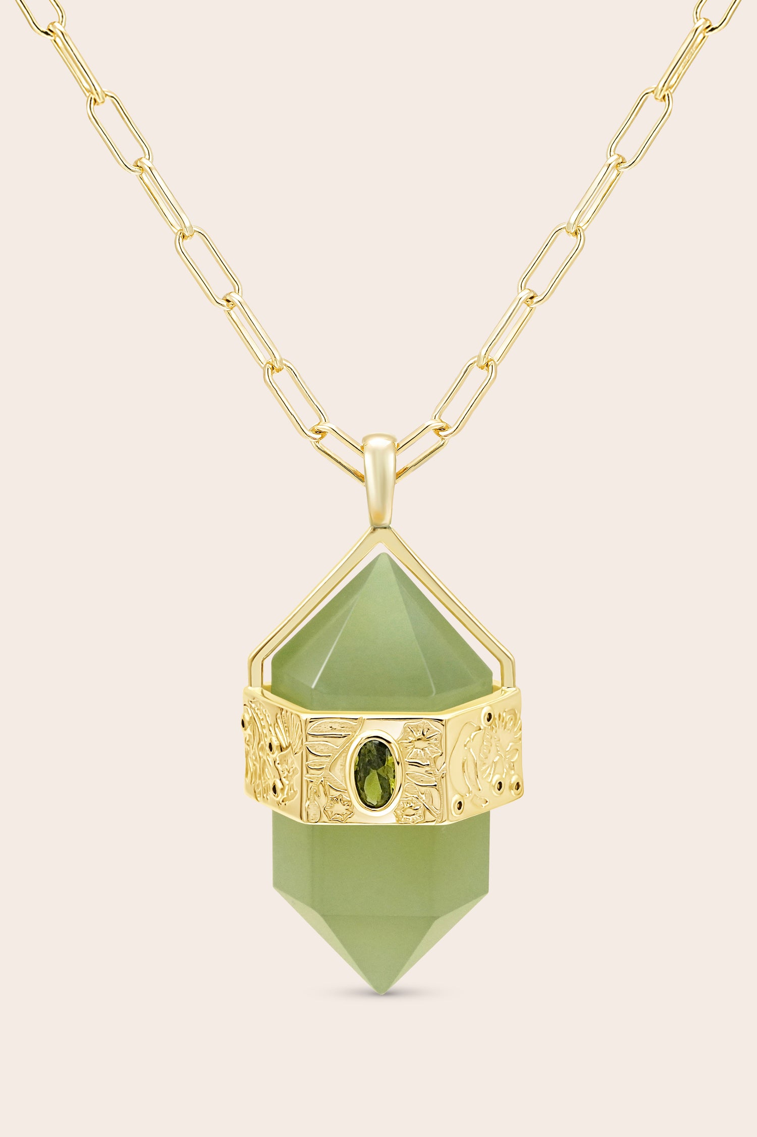 Gold necklace with a green pendant on a beige background