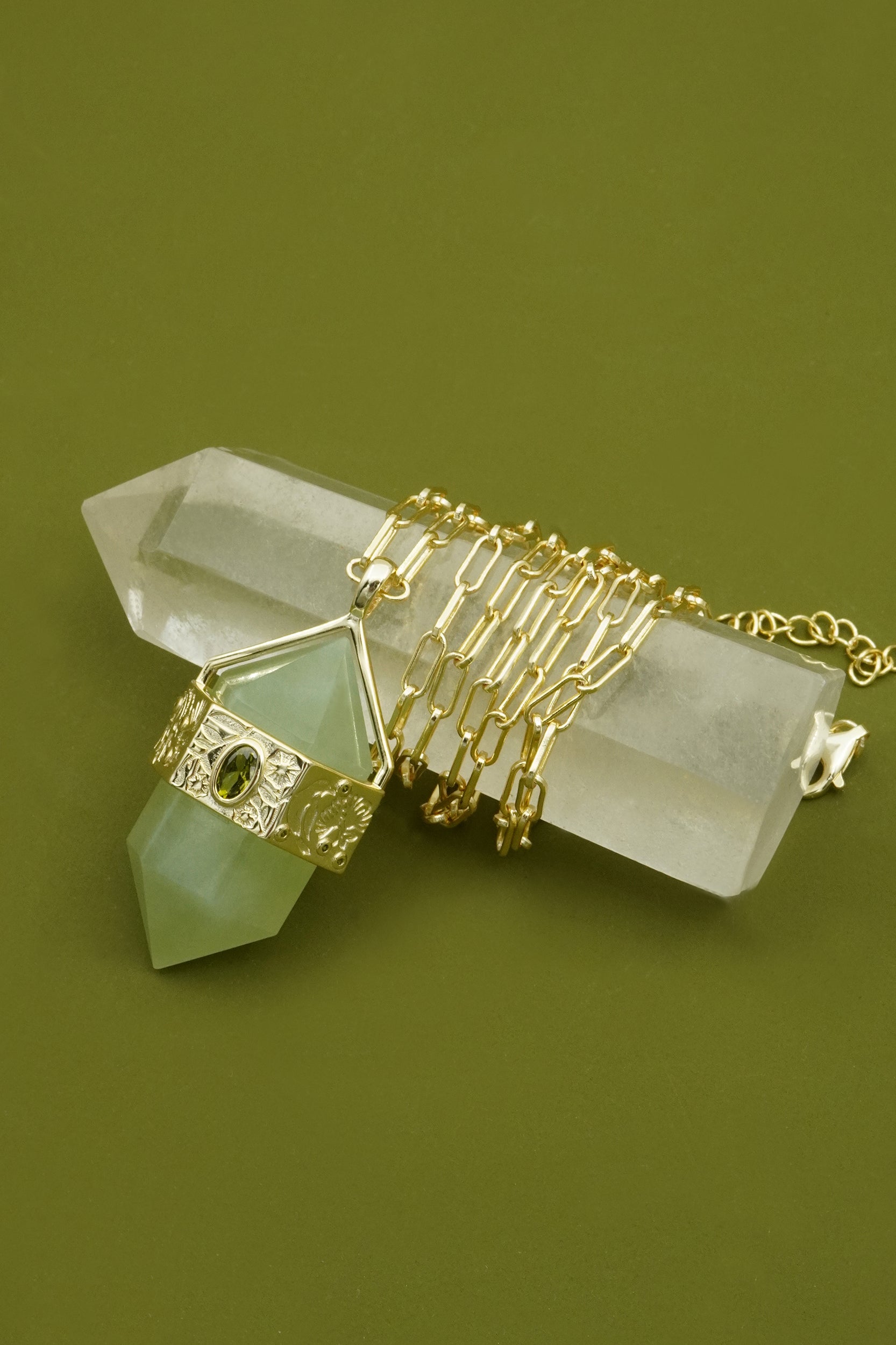 Gold necklace and green crystal on a green background