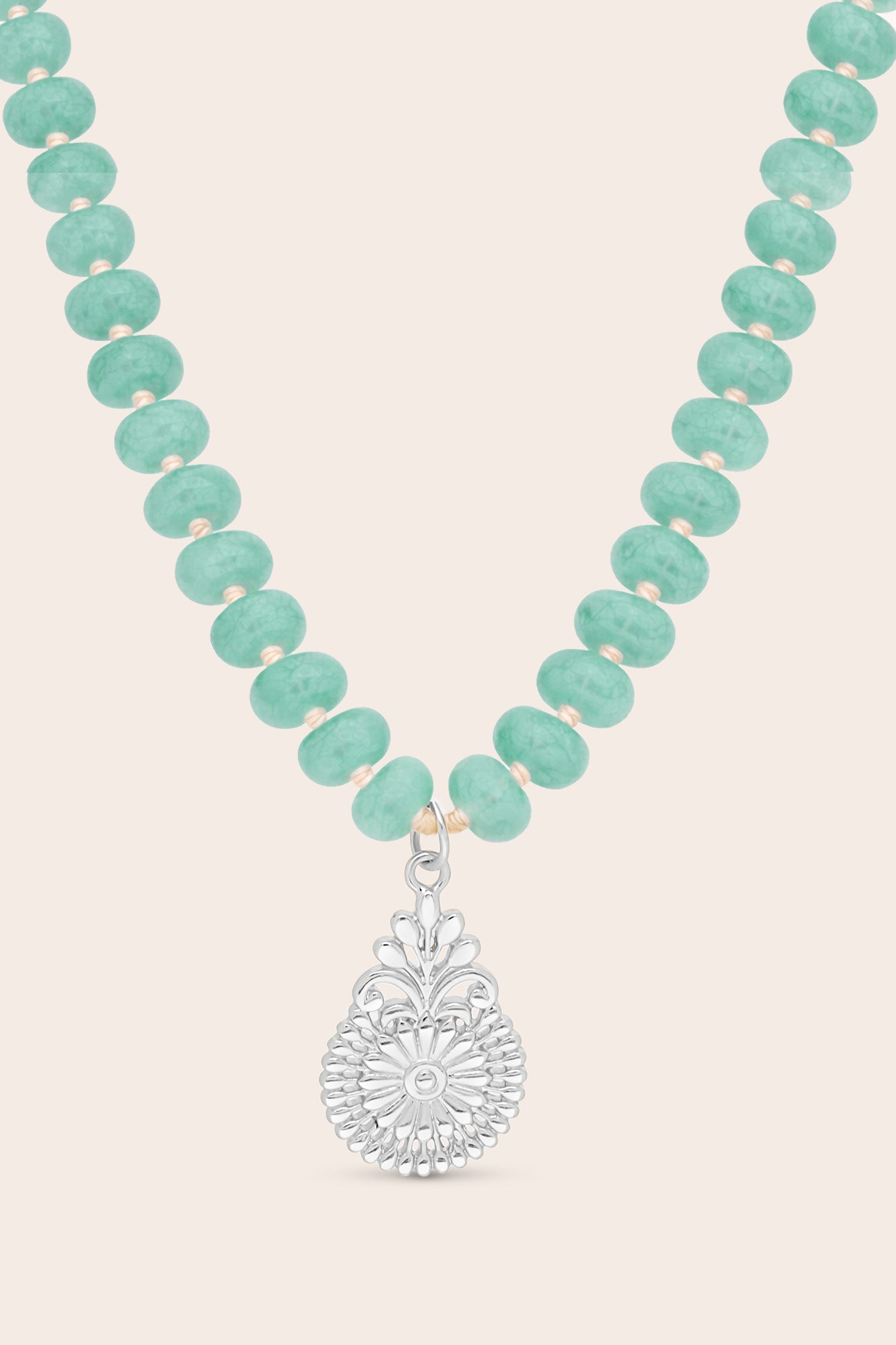 Turquoise crystals beaded necklace with a silver pendant on a light beige background