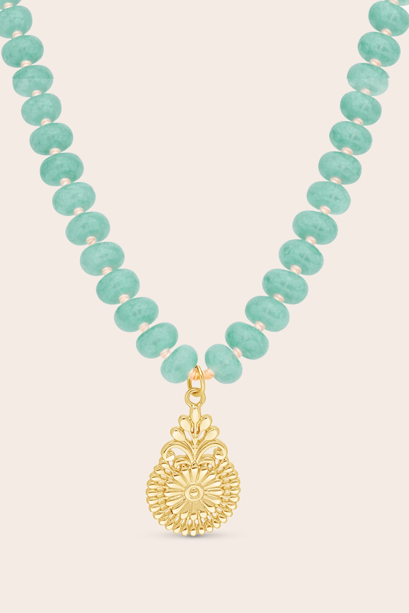 Turquoise beaded necklace with a gold pendant on a beige background