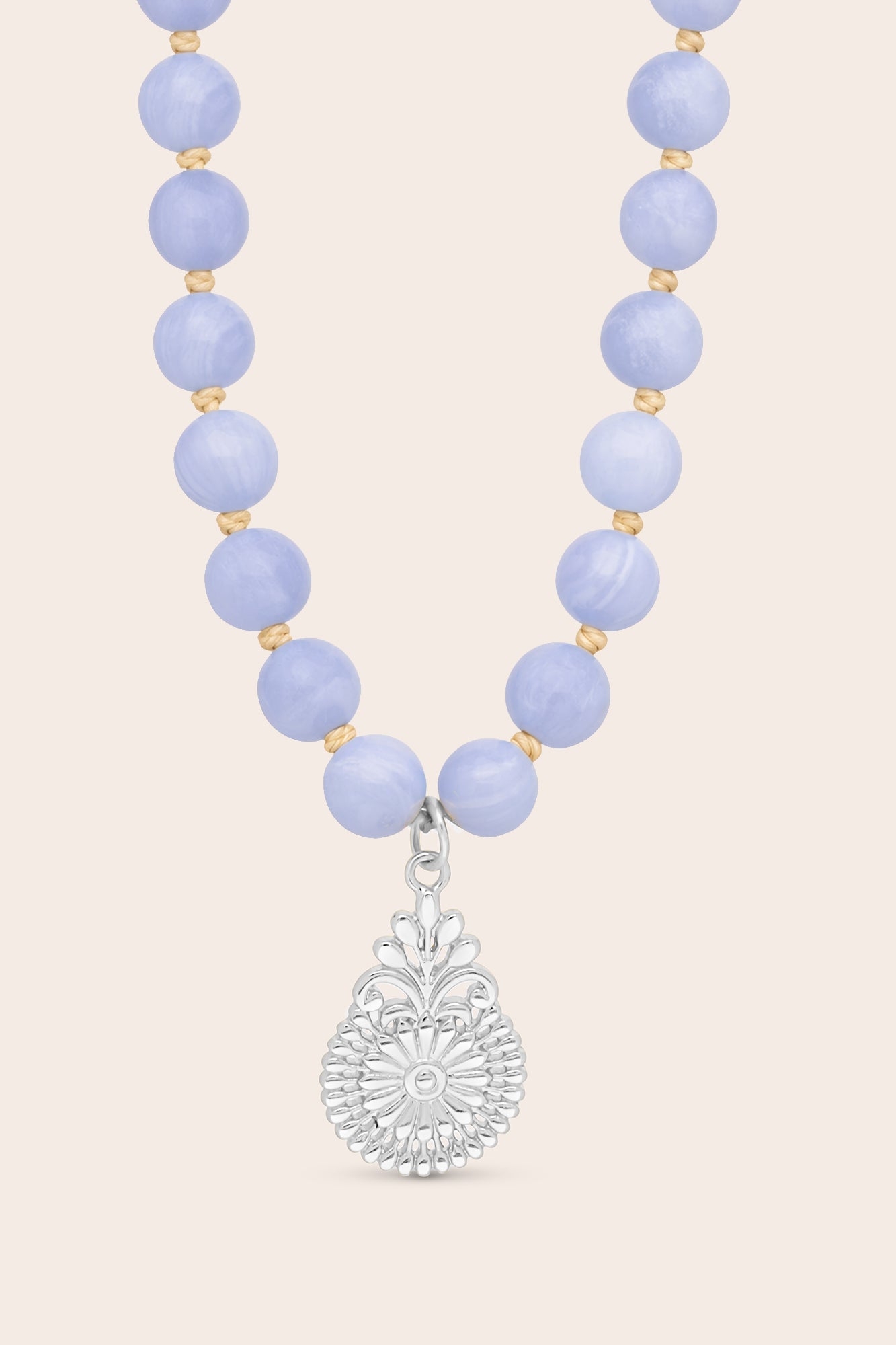 Mala Necklace with blue lace agate beads and a silver flower pendant on a light pink background