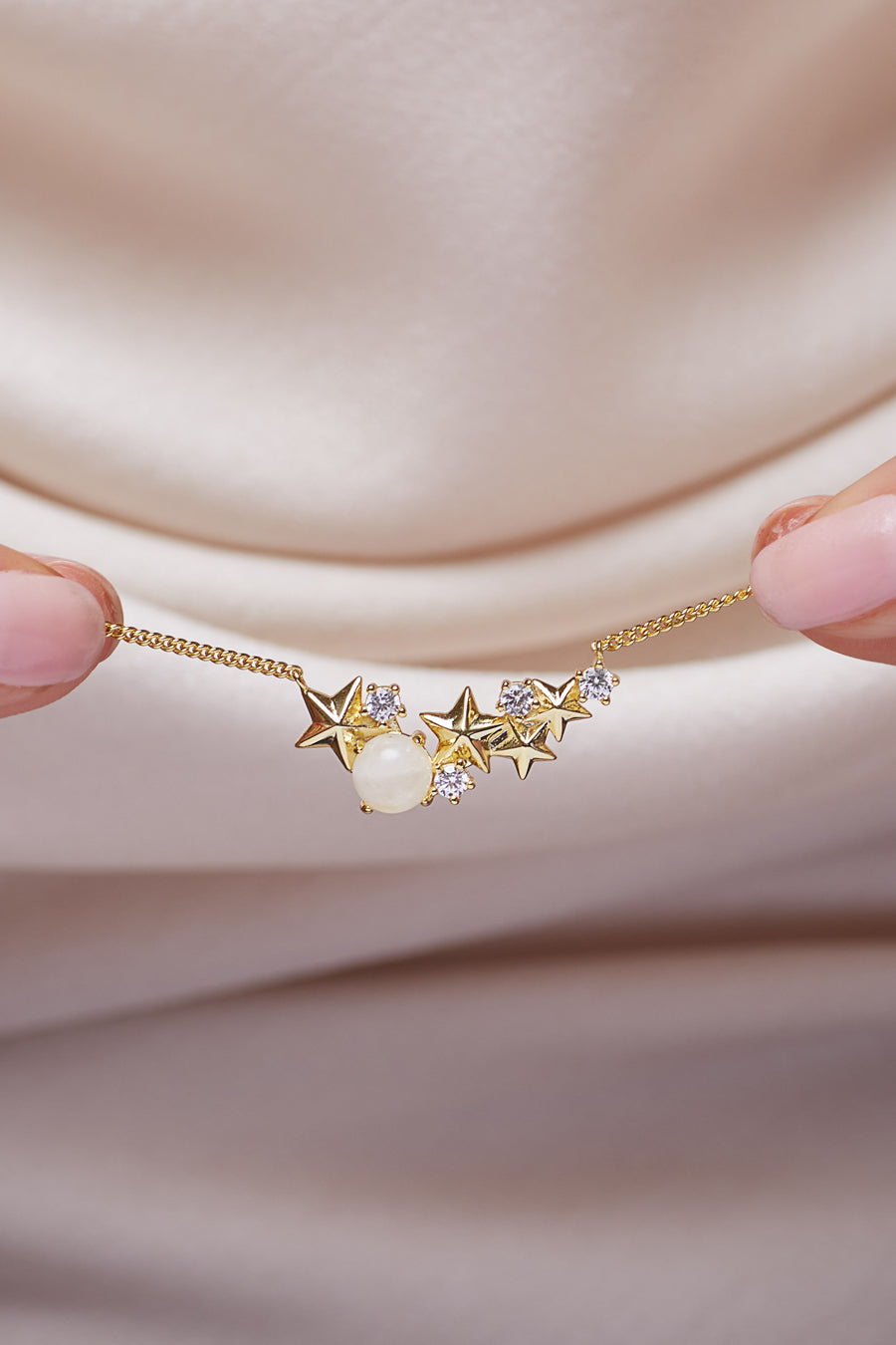 Gold Matariki Necklace on satin background