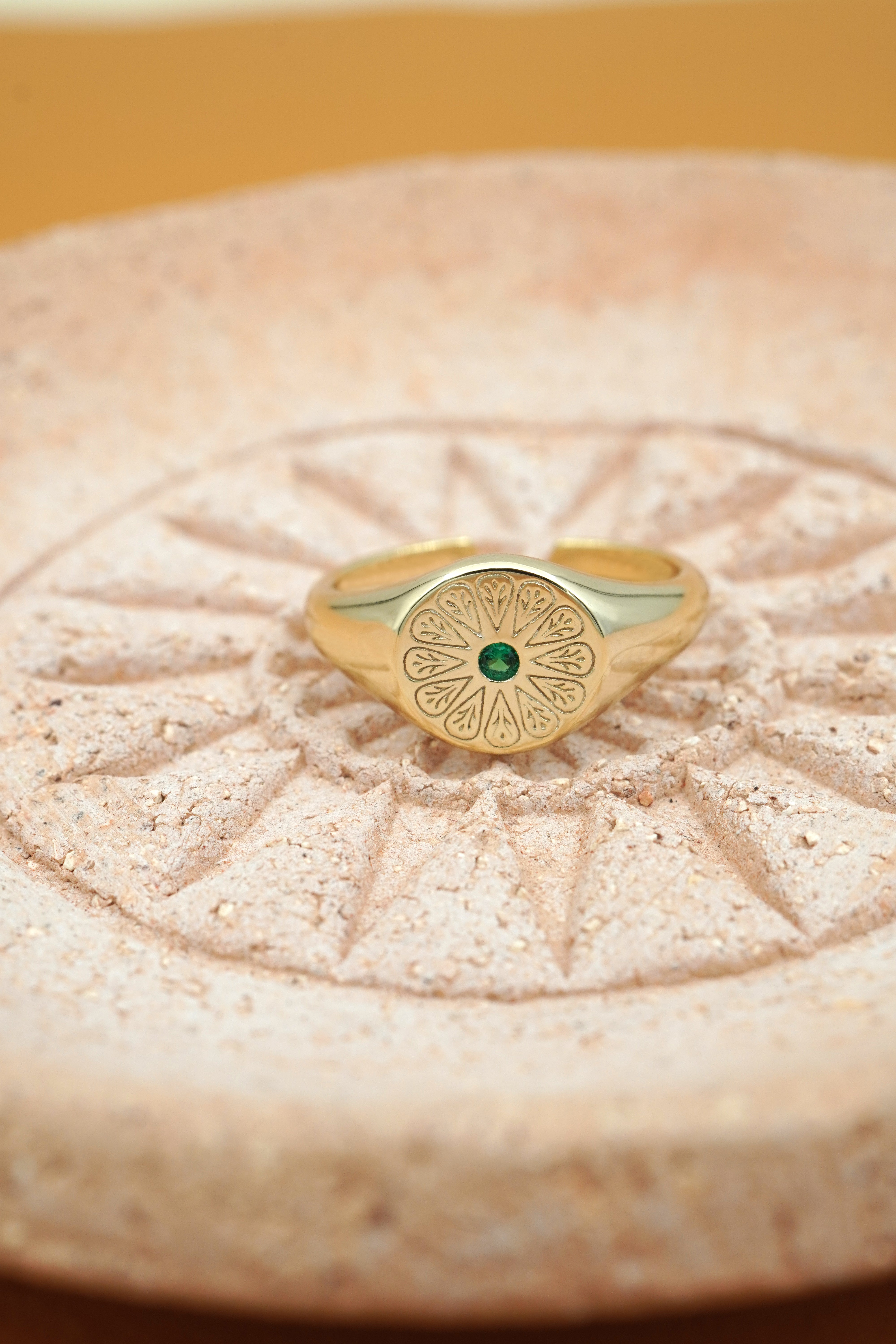 Gold May Emerald Birthstone Ring on peach pottery