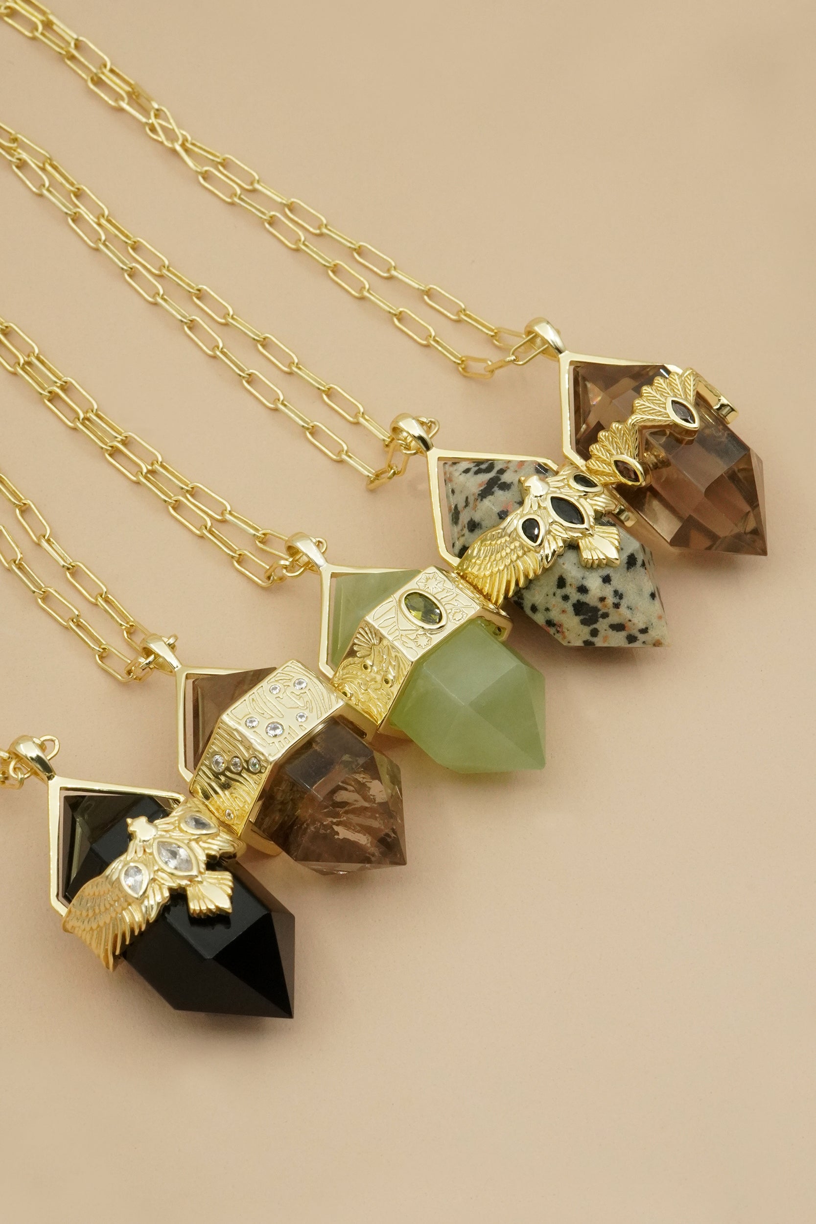 Gold crystal gemstone large pendulum necklaces on beige background.