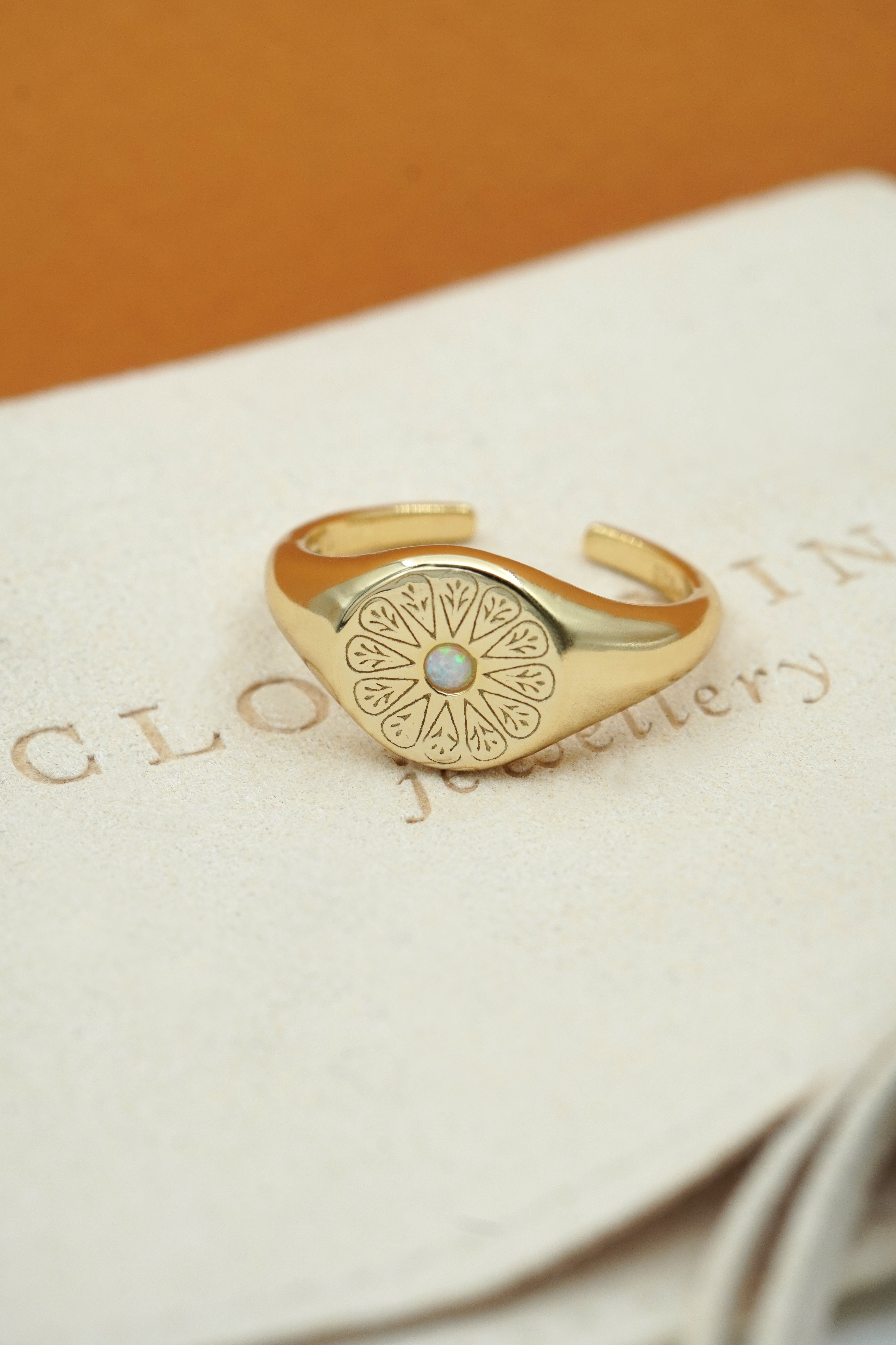 Gold October Opal Signet Birthstone Ring on cream fabric