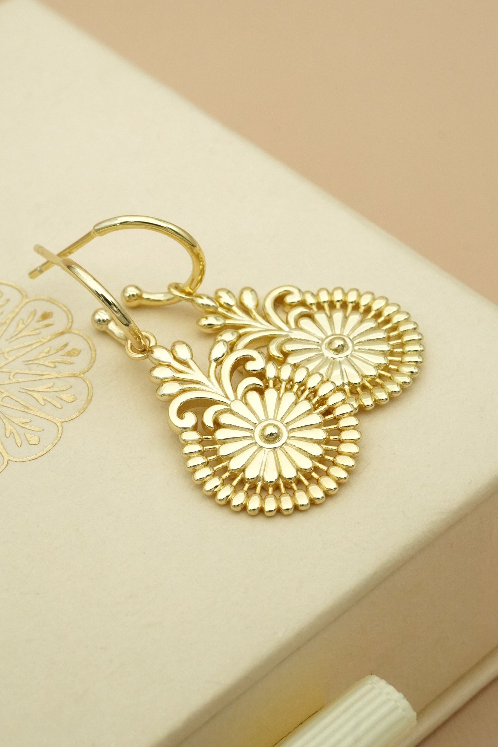 14k Gold filigree flower-shaped earrings on a beige box