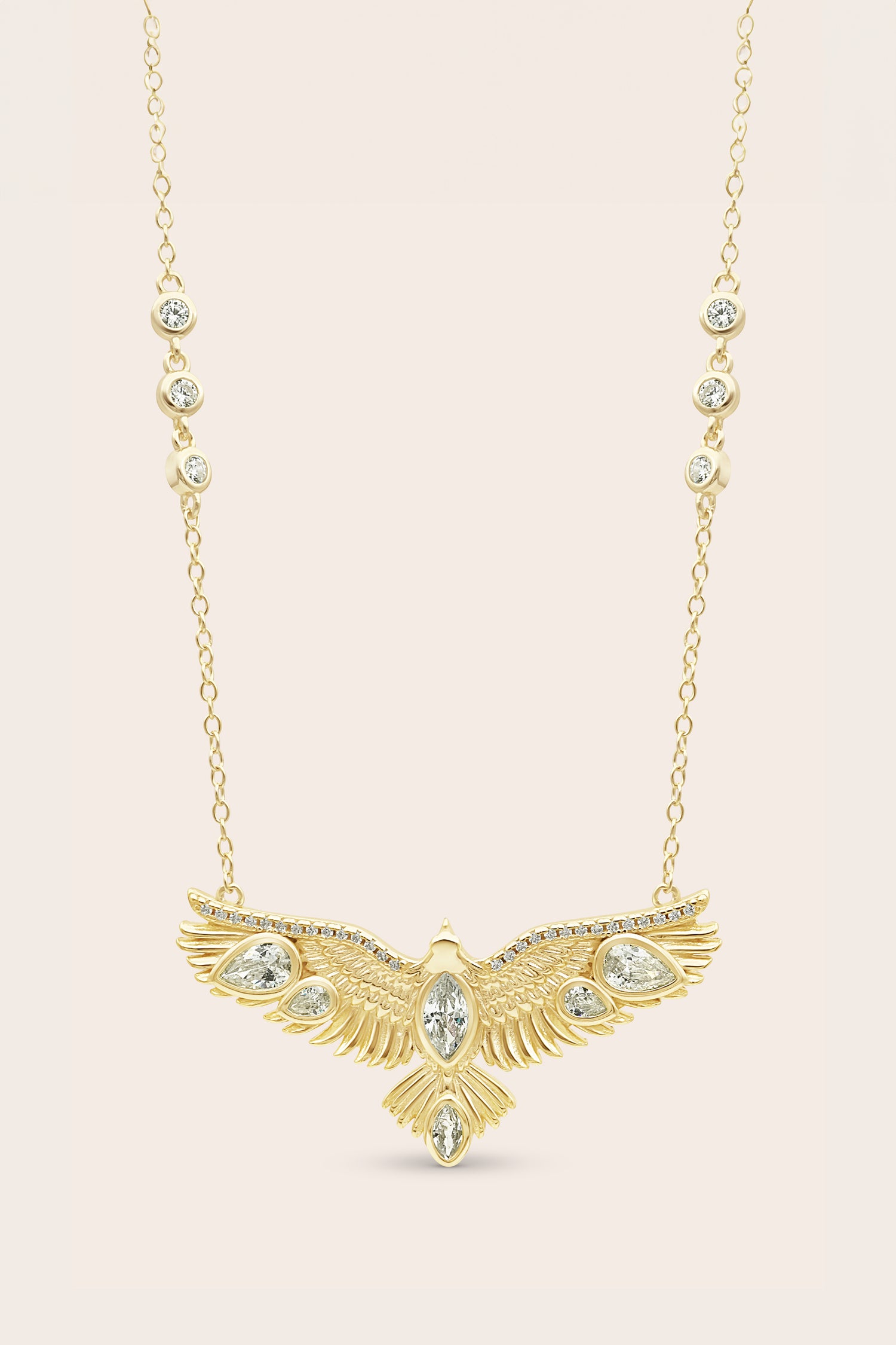 Gold necklace with an eagle-shaped pendant on a beige background