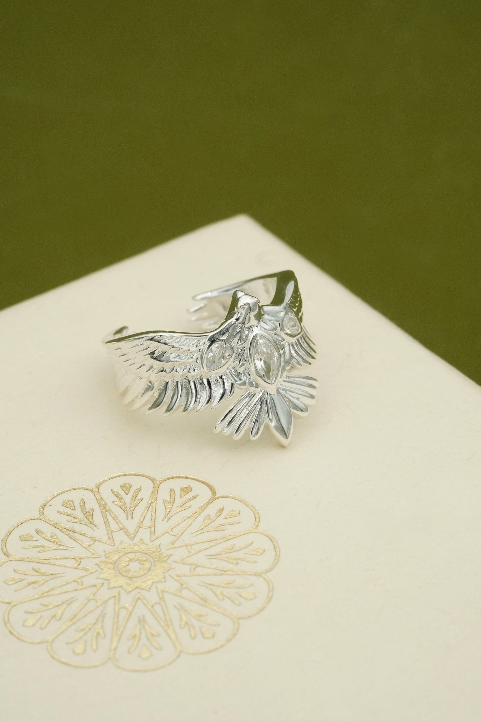Silver phoenix rising ring with eagle design on a textured surface