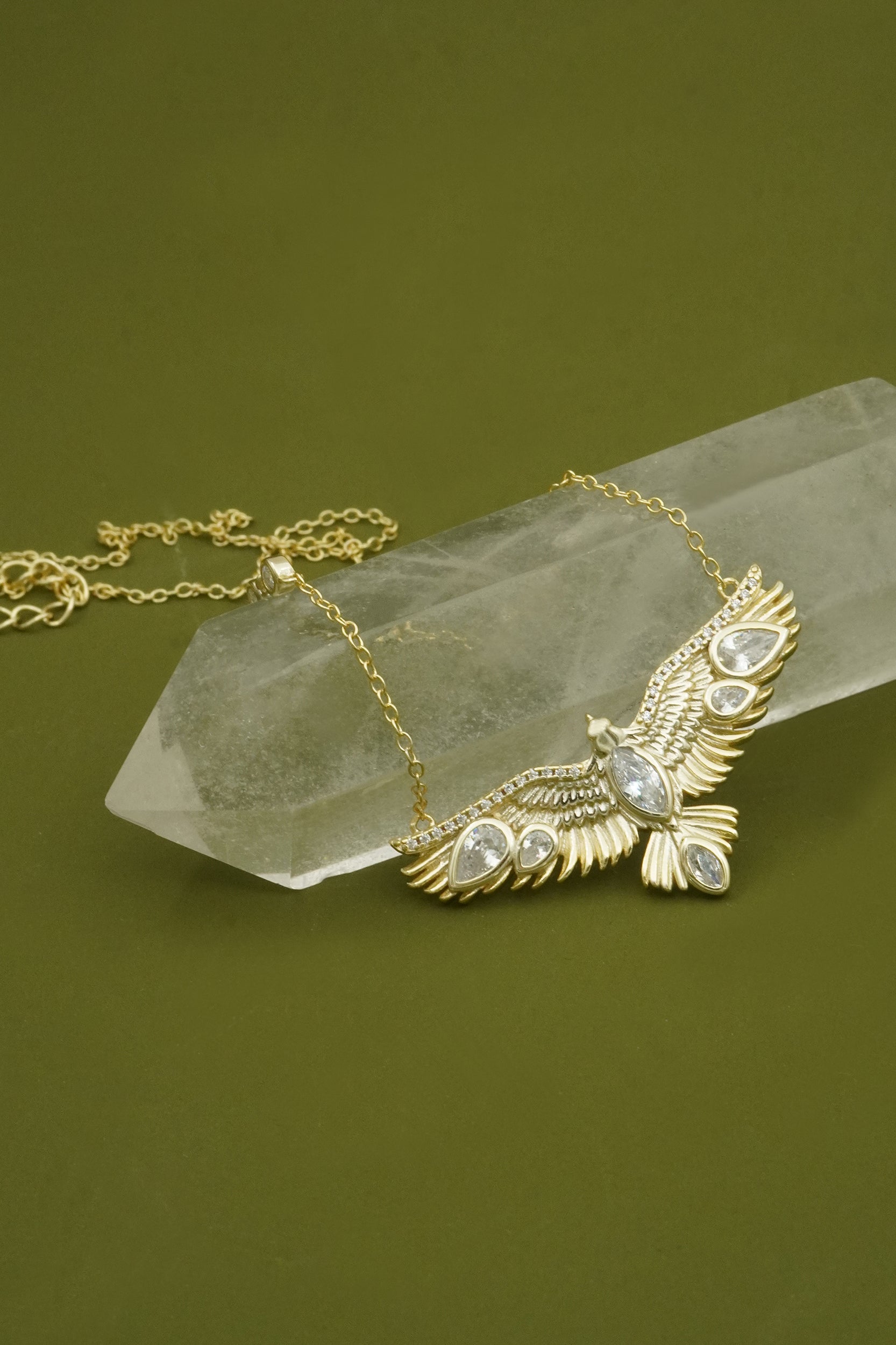 Gold necklace with an eagle pendant on a green background
