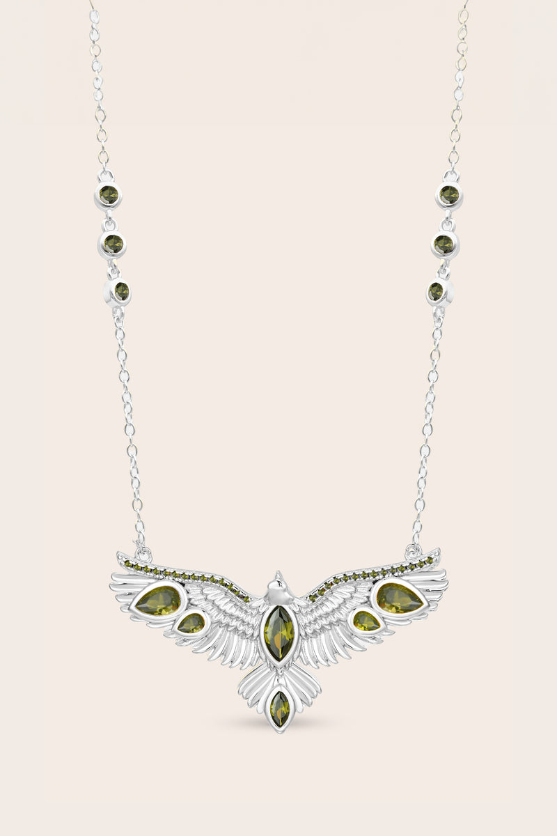 Silver hawk necklace with green gemstone pendant on a light pink background
