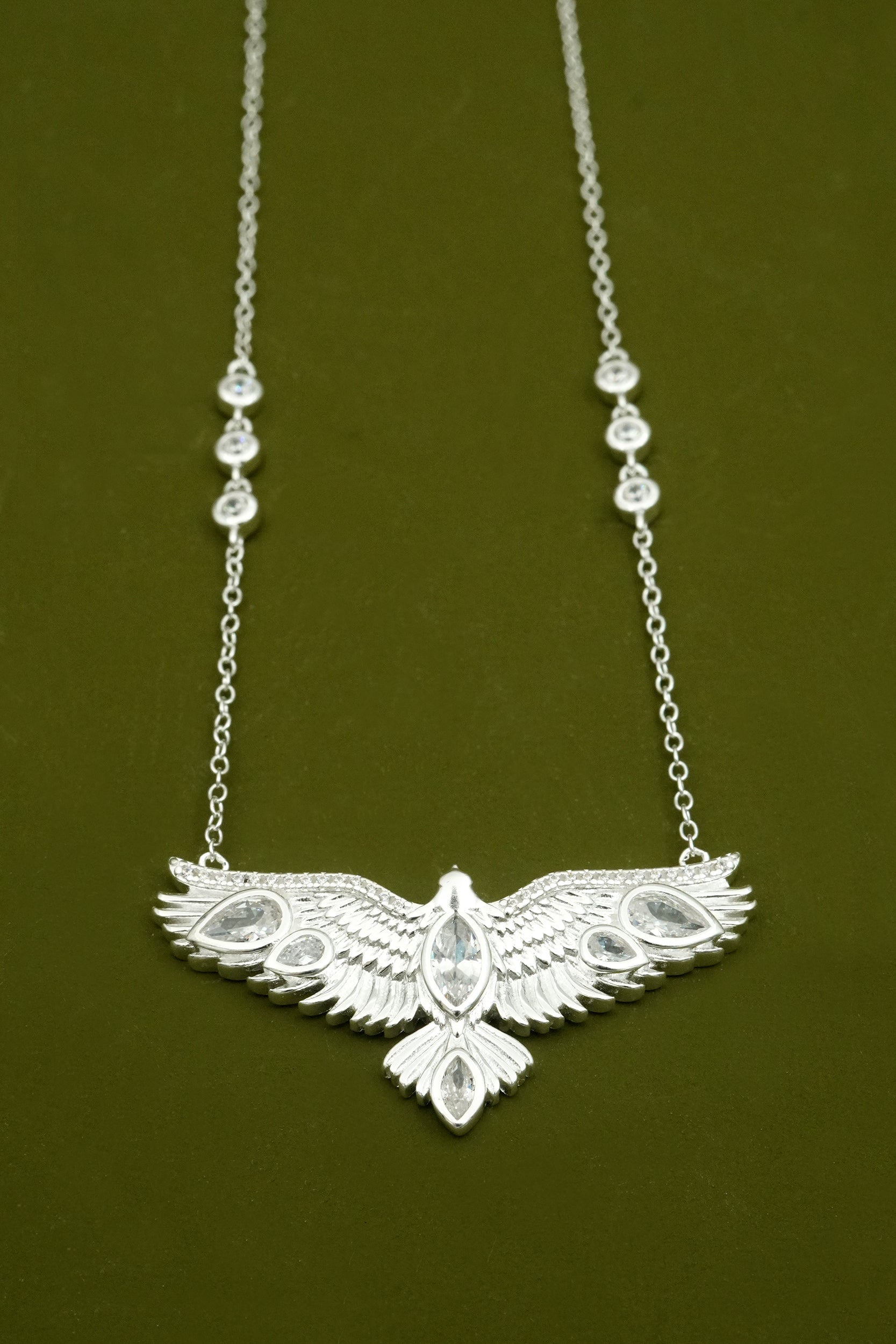 Silver necklace with an eagle pendant on a dark green background