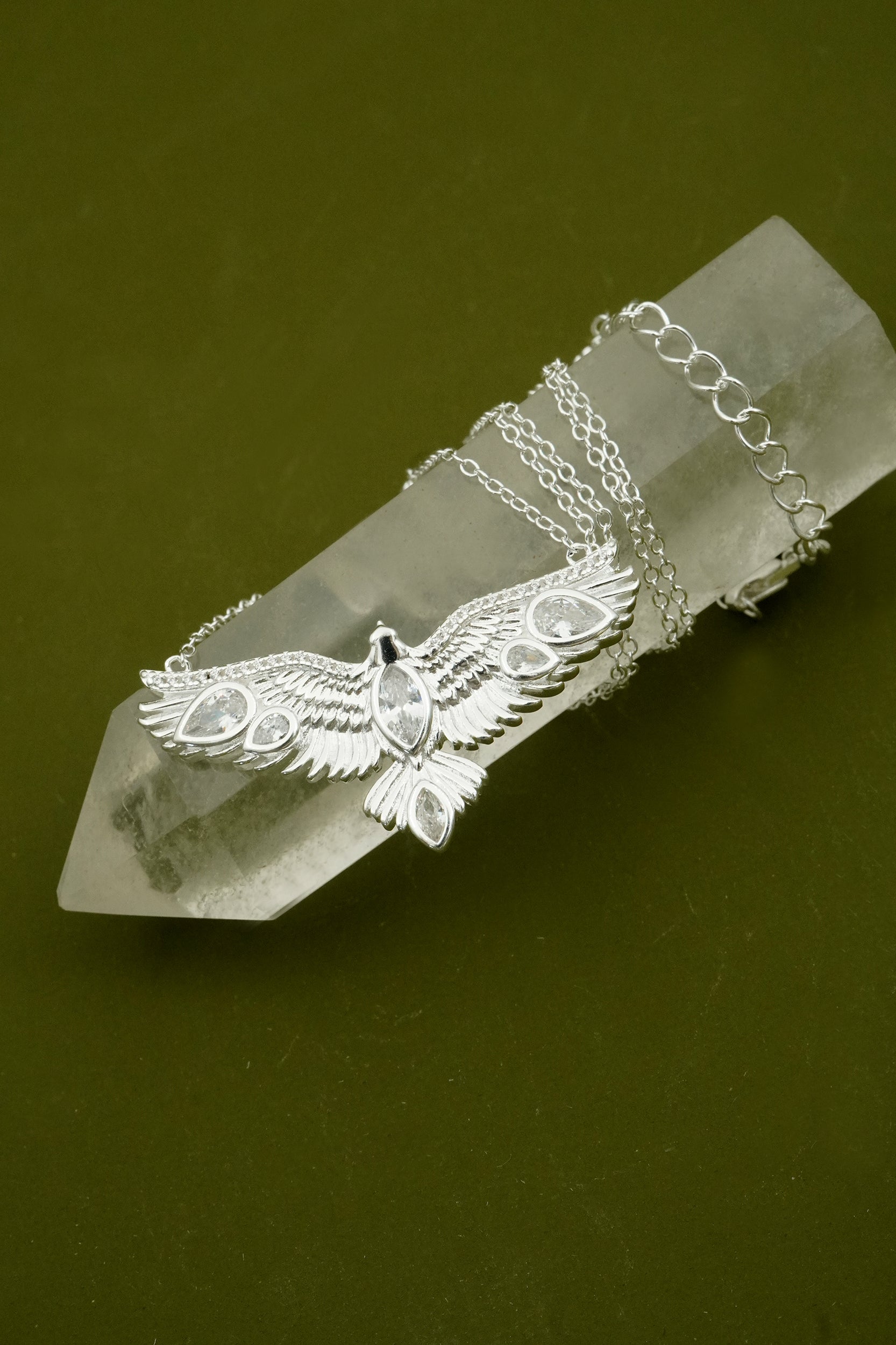 Silver eagle pendant necklace on a crystal with a green background