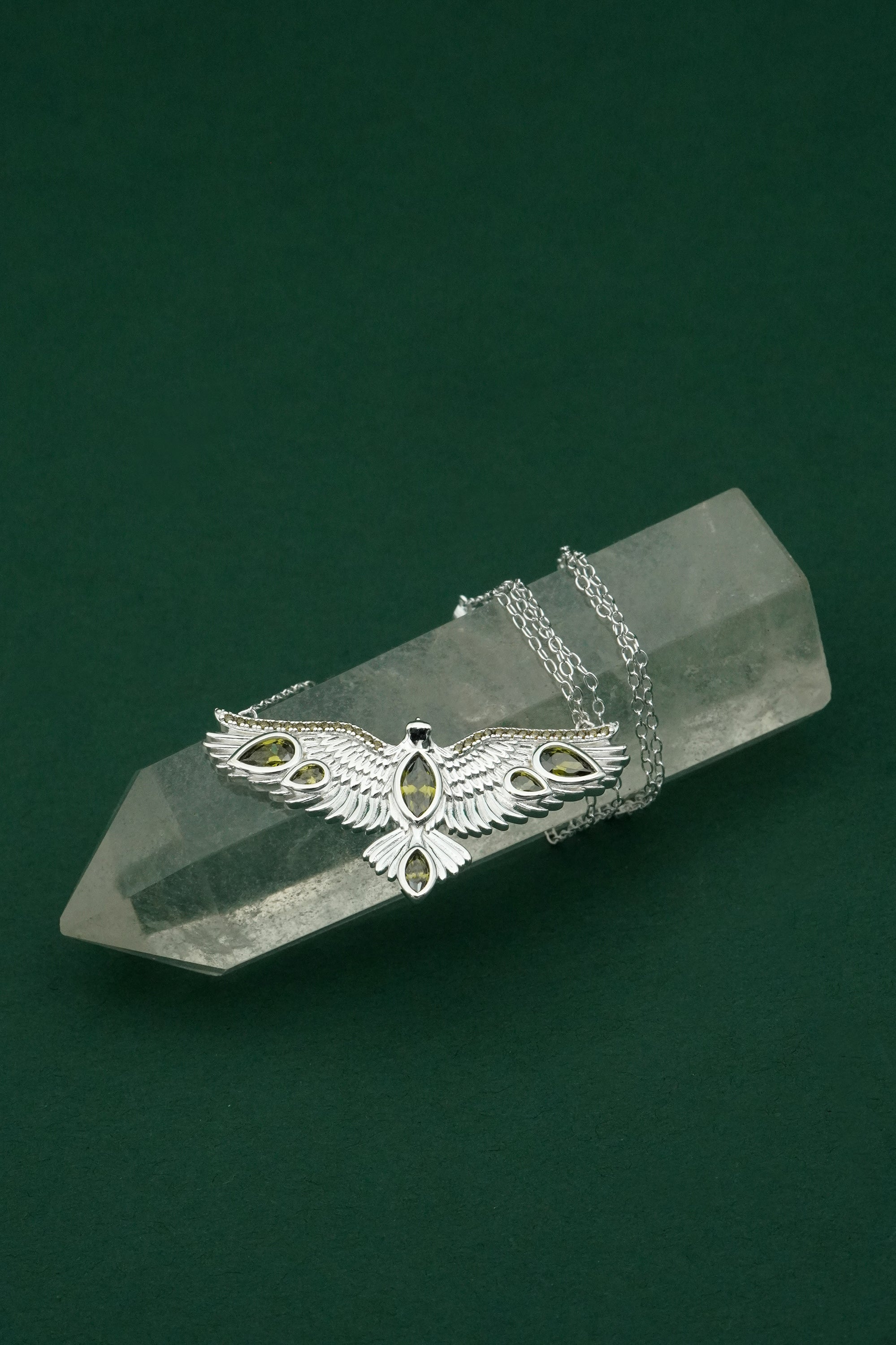 Silver hawk necklace with an eagle pendant on a crystal block against a green background