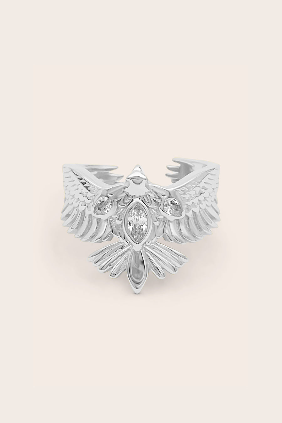 Silver hawk bird ring with intricate design on a light beige background