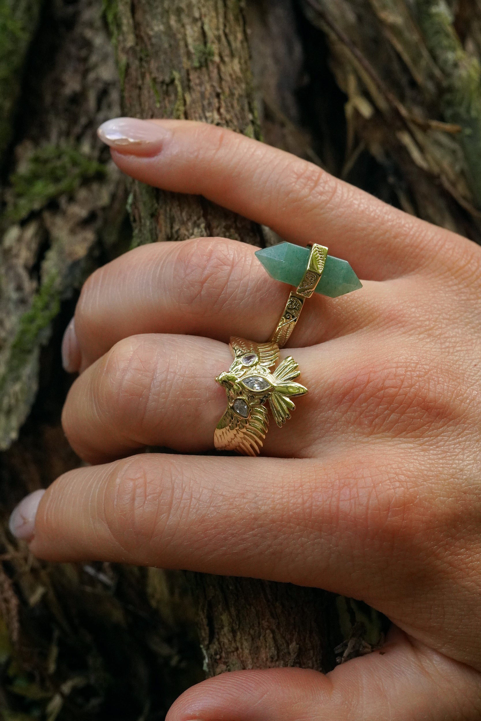 hand wearing a hawk and green crustal ring on a tree background