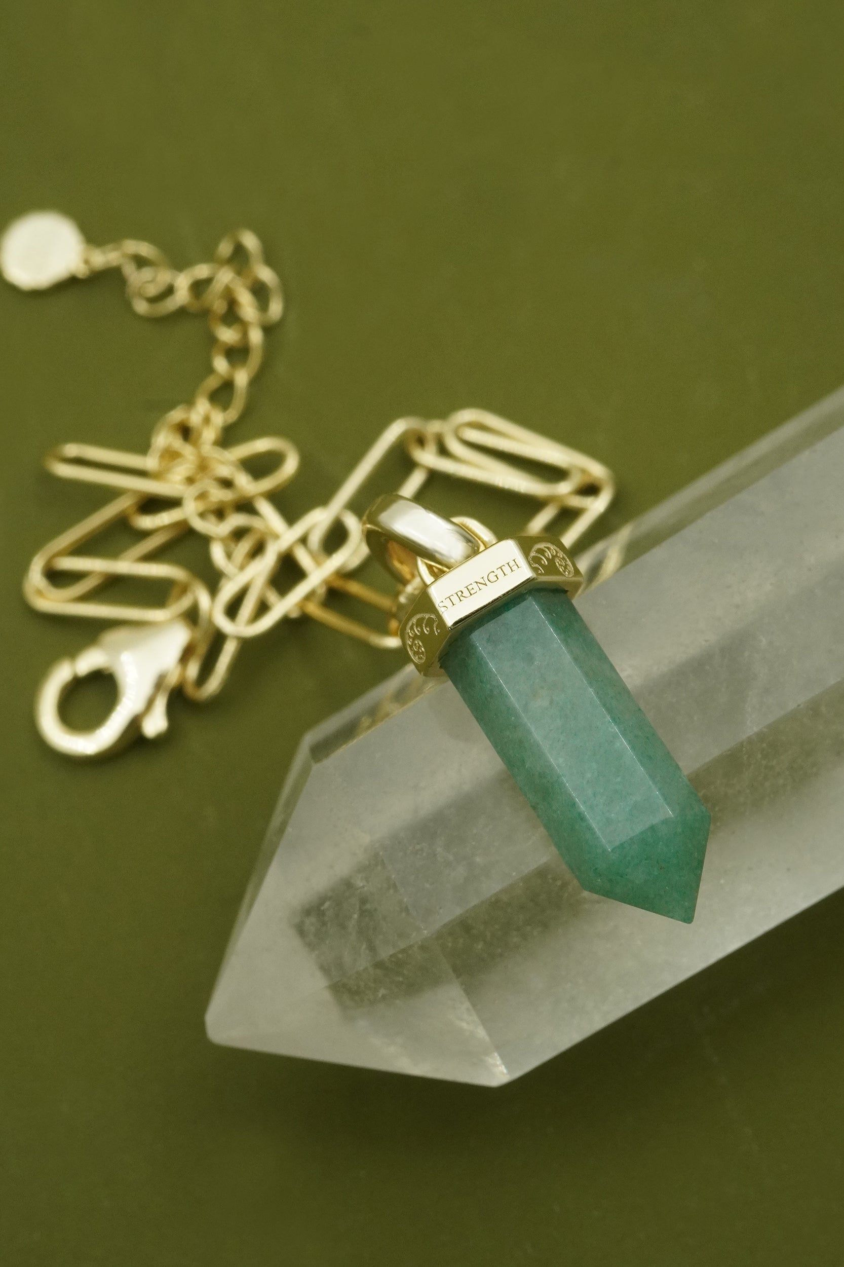 Bracelet with a green aventurine crystal pendant on a clear crystal base against a green background
