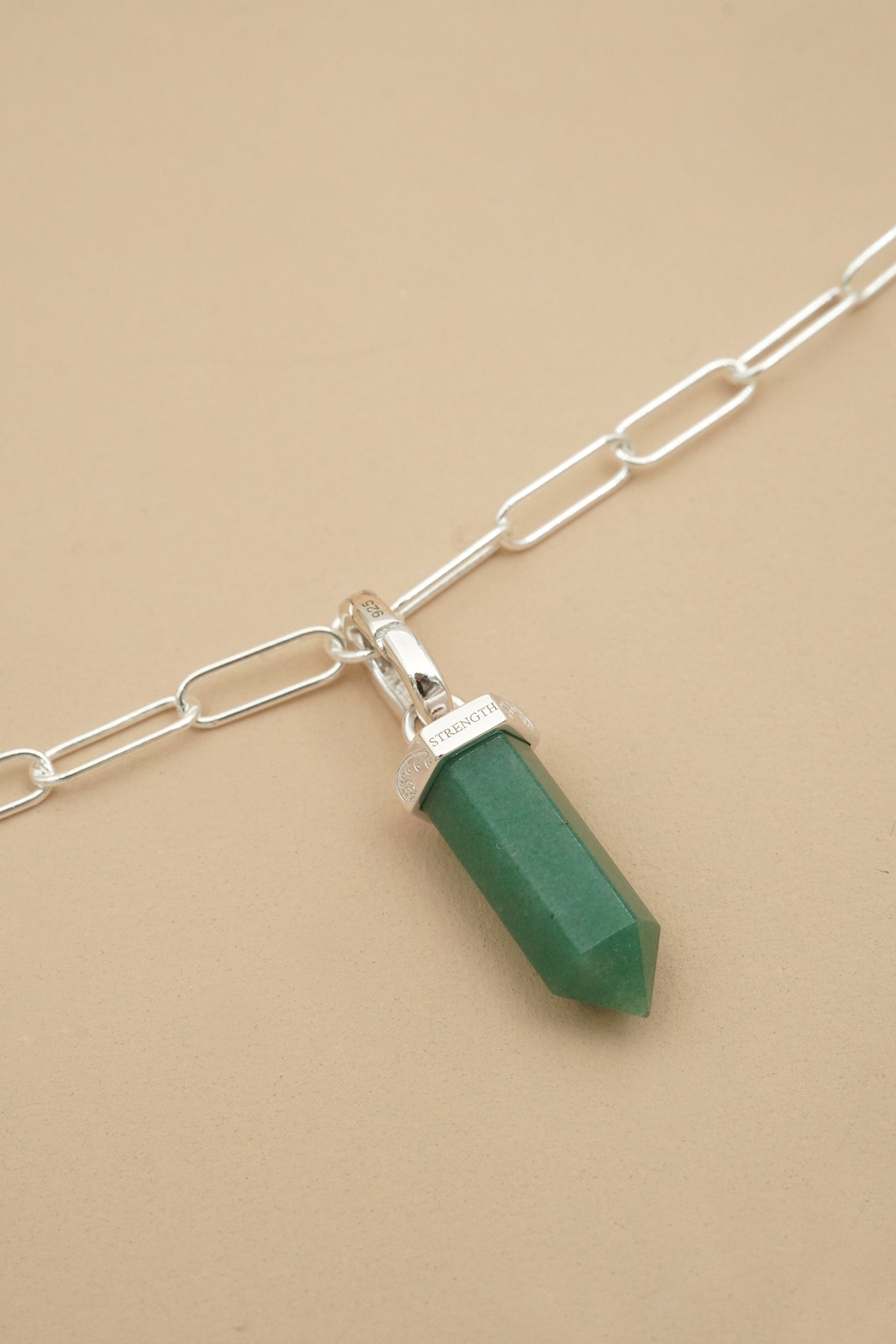 Silver Necklace with a green aventurine crystal pendant on a beige background