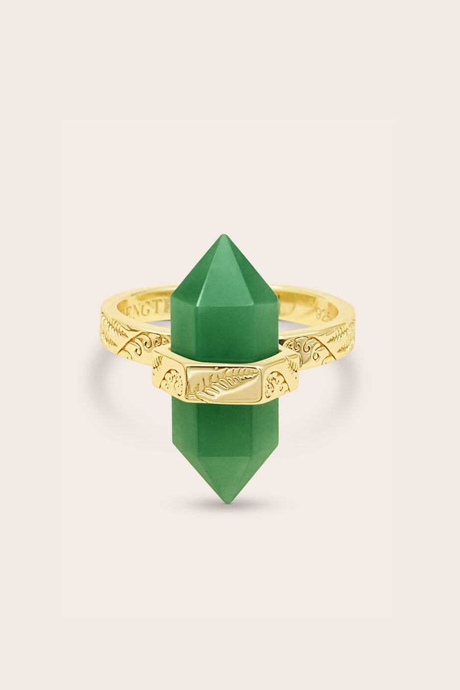 Green aventurine crystal ring with gold band with fern and koru detailing on a beige background