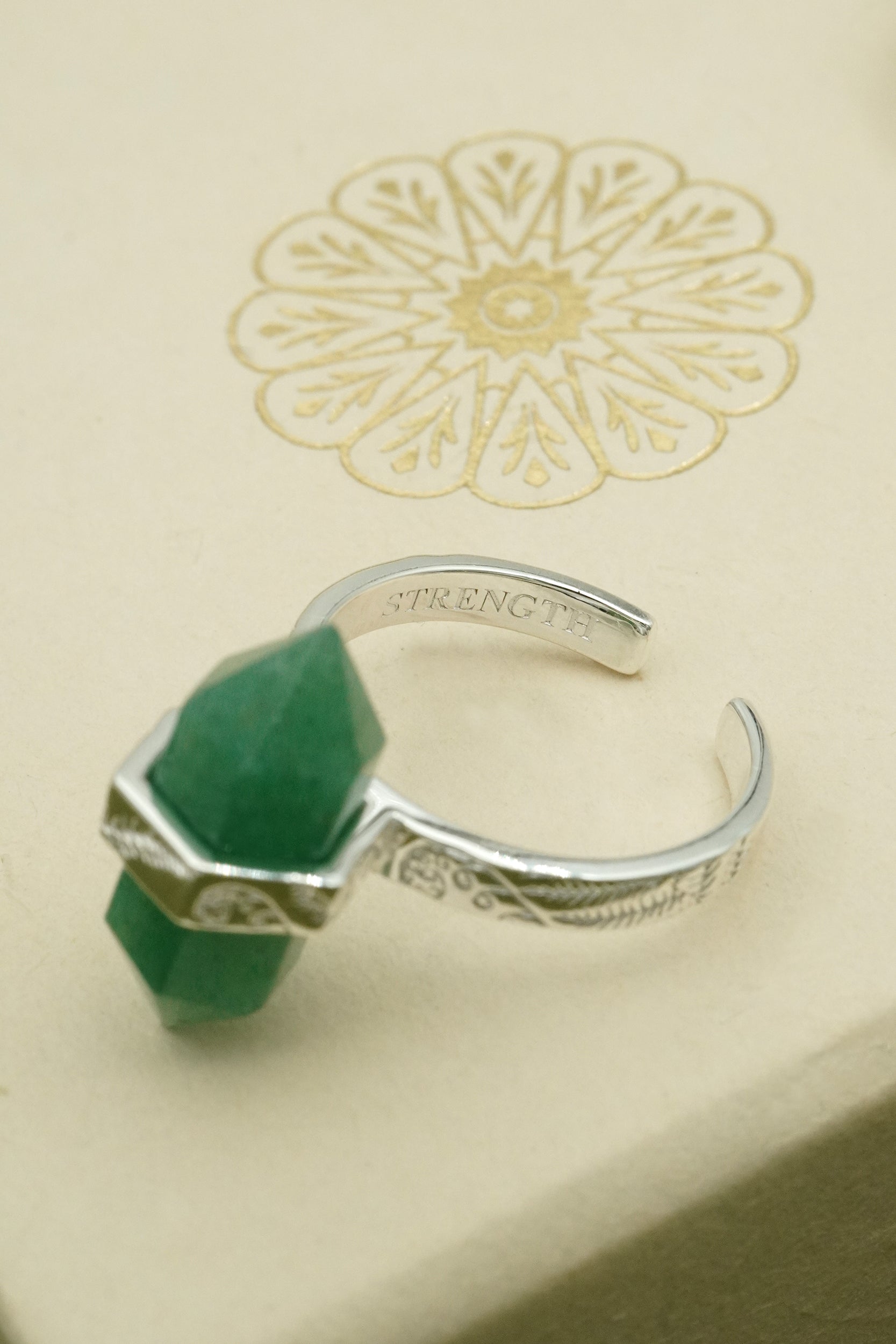 Silver ring with green gemstone on a decorative card