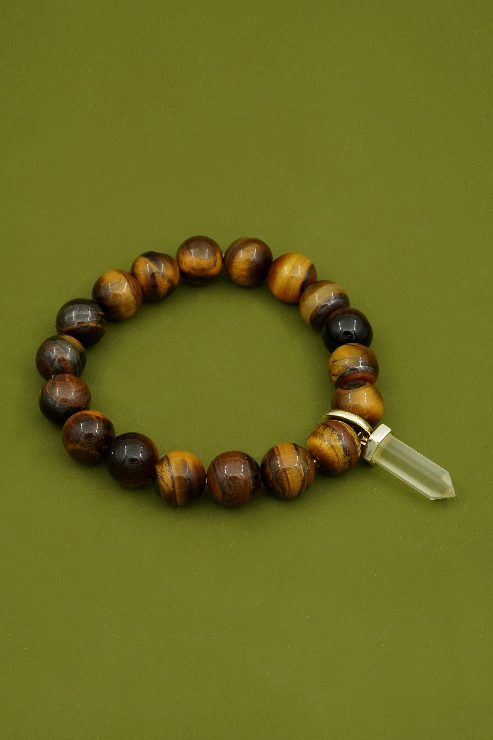 Beaded tiger's eye bracelet with a crystal on a green background