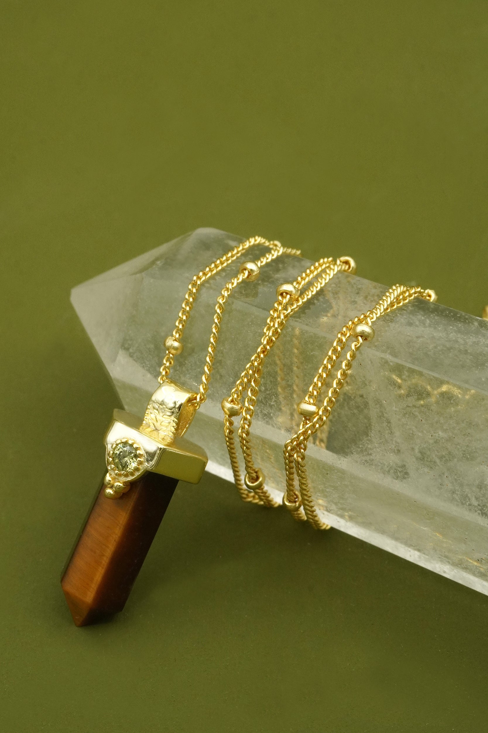 Gold necklaces on a clear crystal with a green background