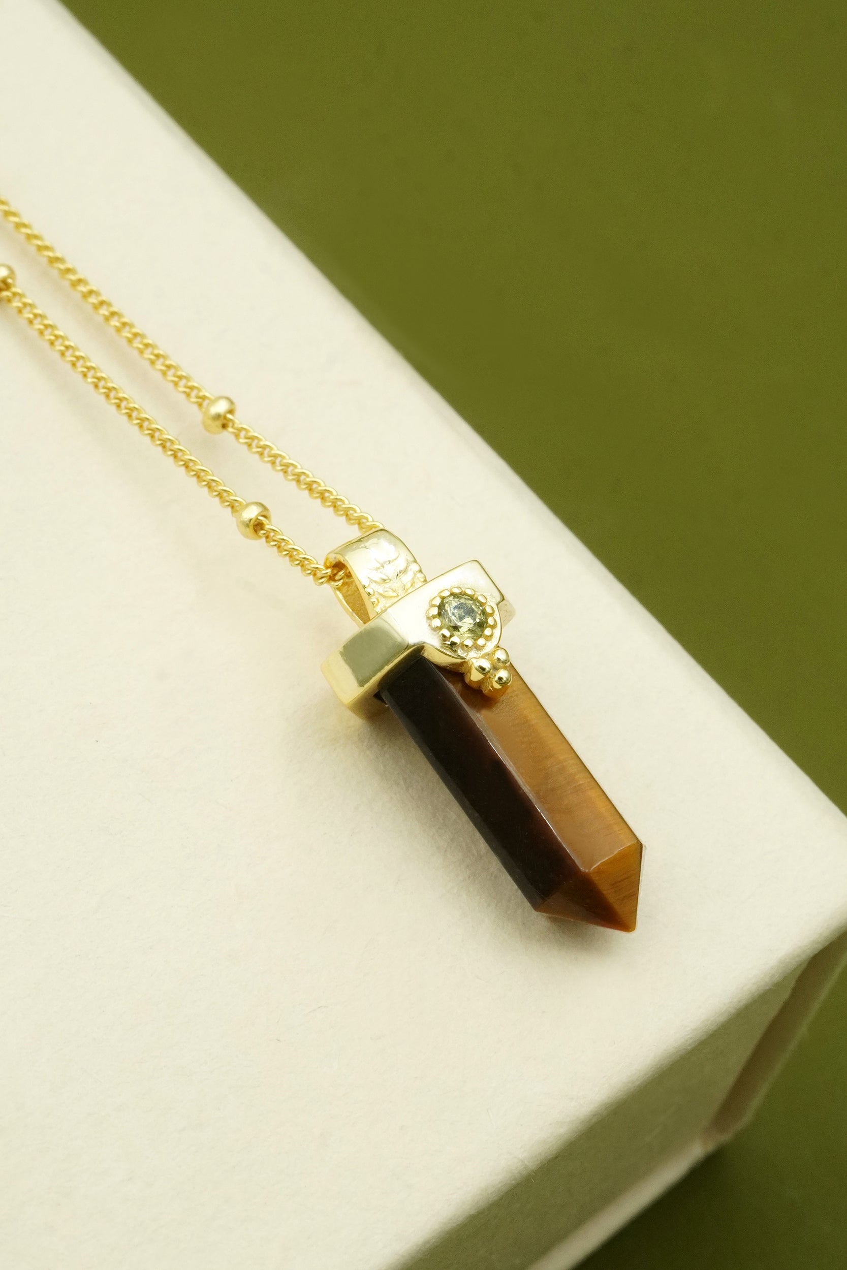 Necklace with a brown tiger's eye crystal pendant on a white surface