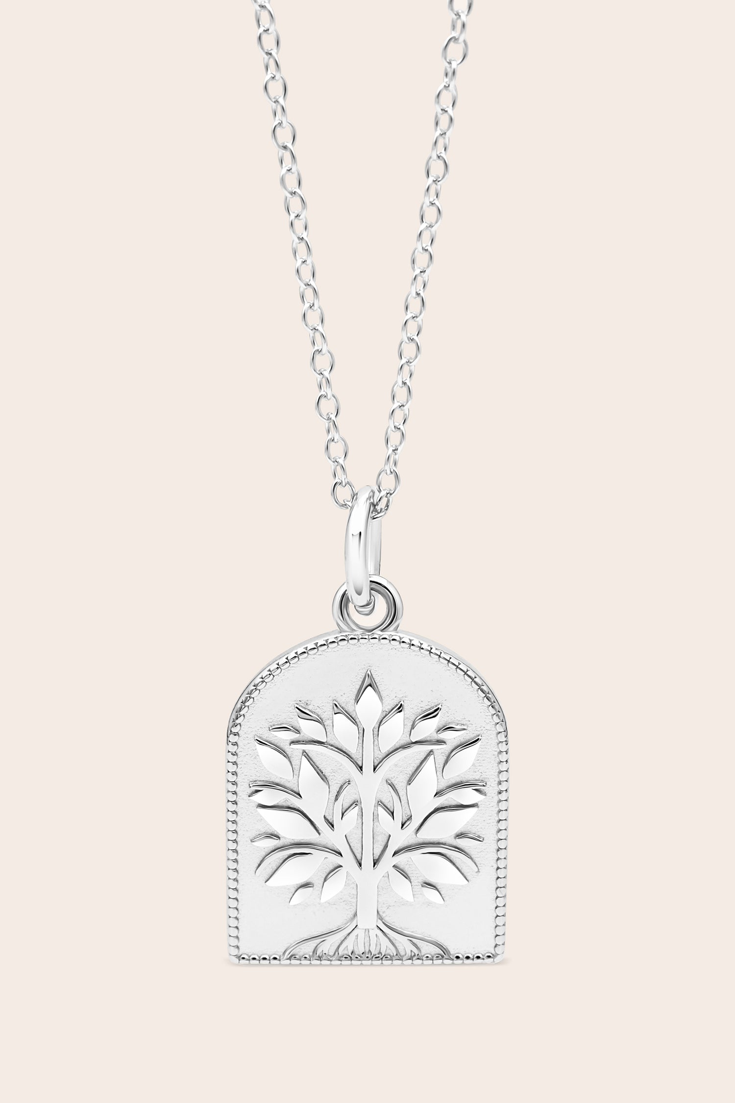 Silver necklace with a tree-of-life pendant on a light pink background