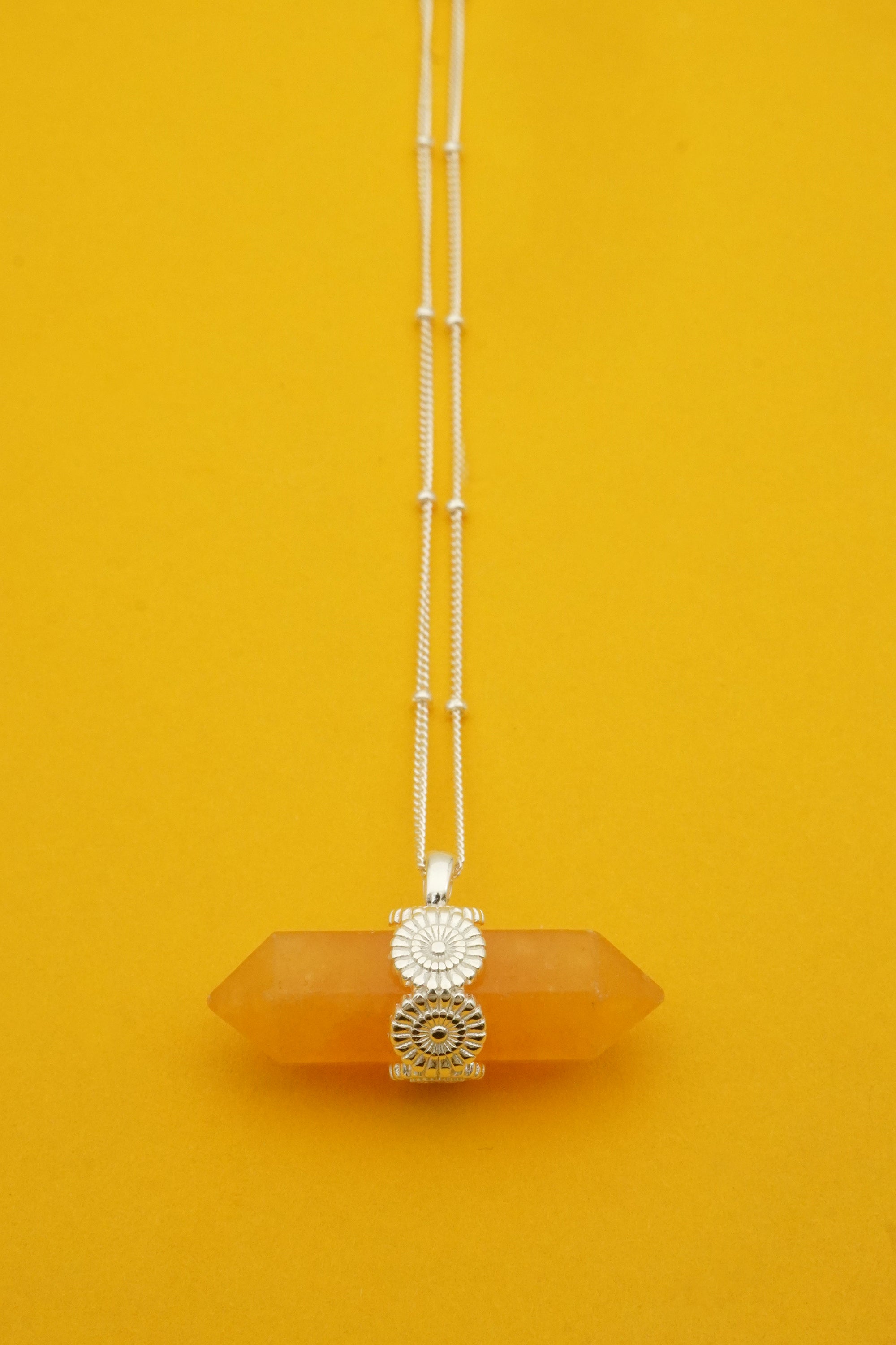 Necklace with a yellow crystal pendant on an orange background