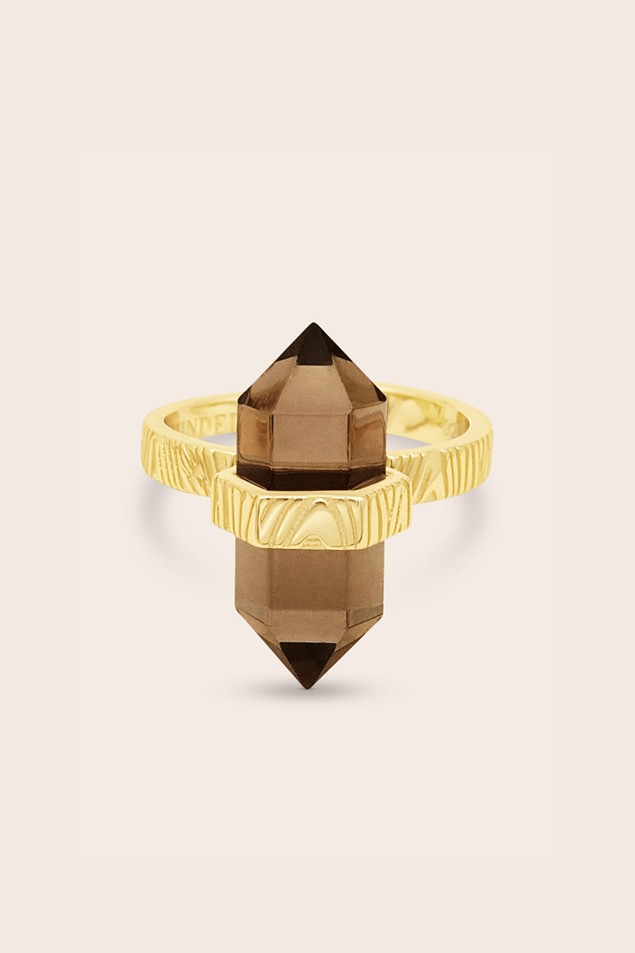 Gold ring with a smoky quartz crystal on a beige background