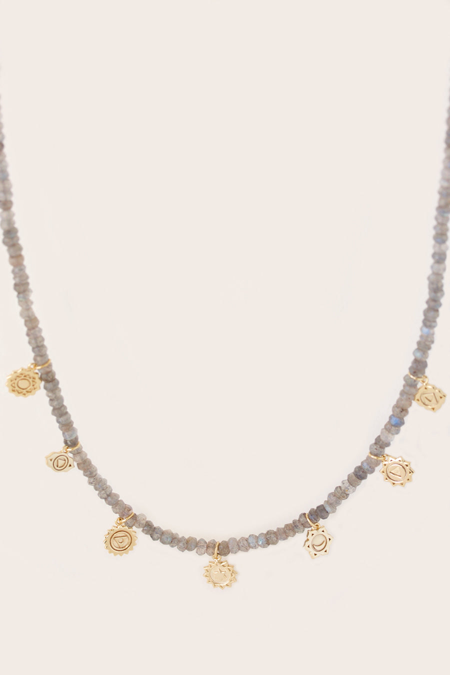 Gold Chakra Necklace with labradorite beads and gold charms on cream background.